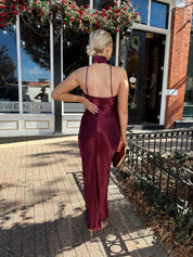 Woman wearing plum satin maxi dress with halter neckline.