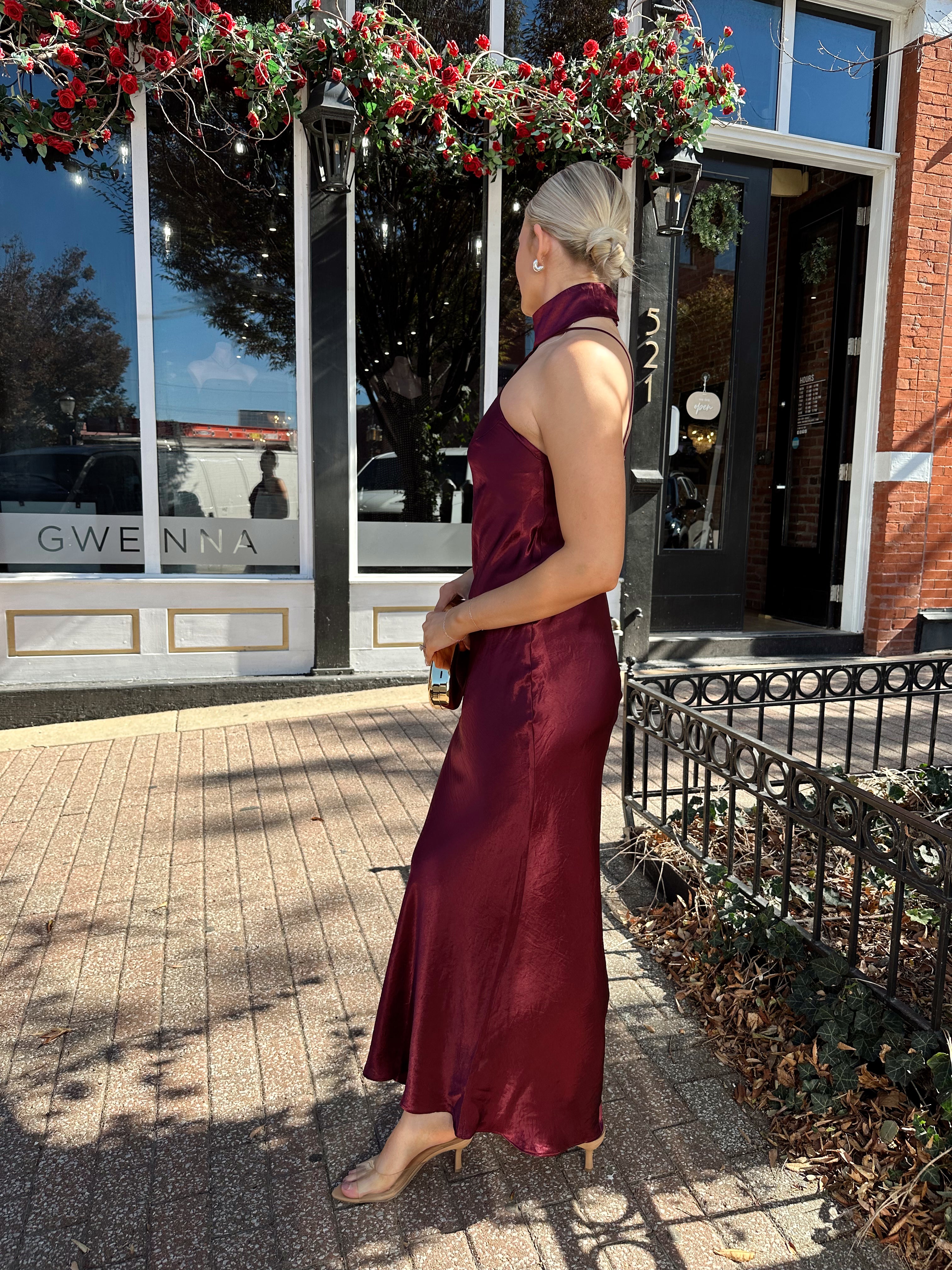Woman wearing plum satin maxi dress with halter neckline.