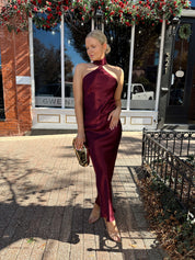 Woman wearing plum satin maxi dress with halter neckline.