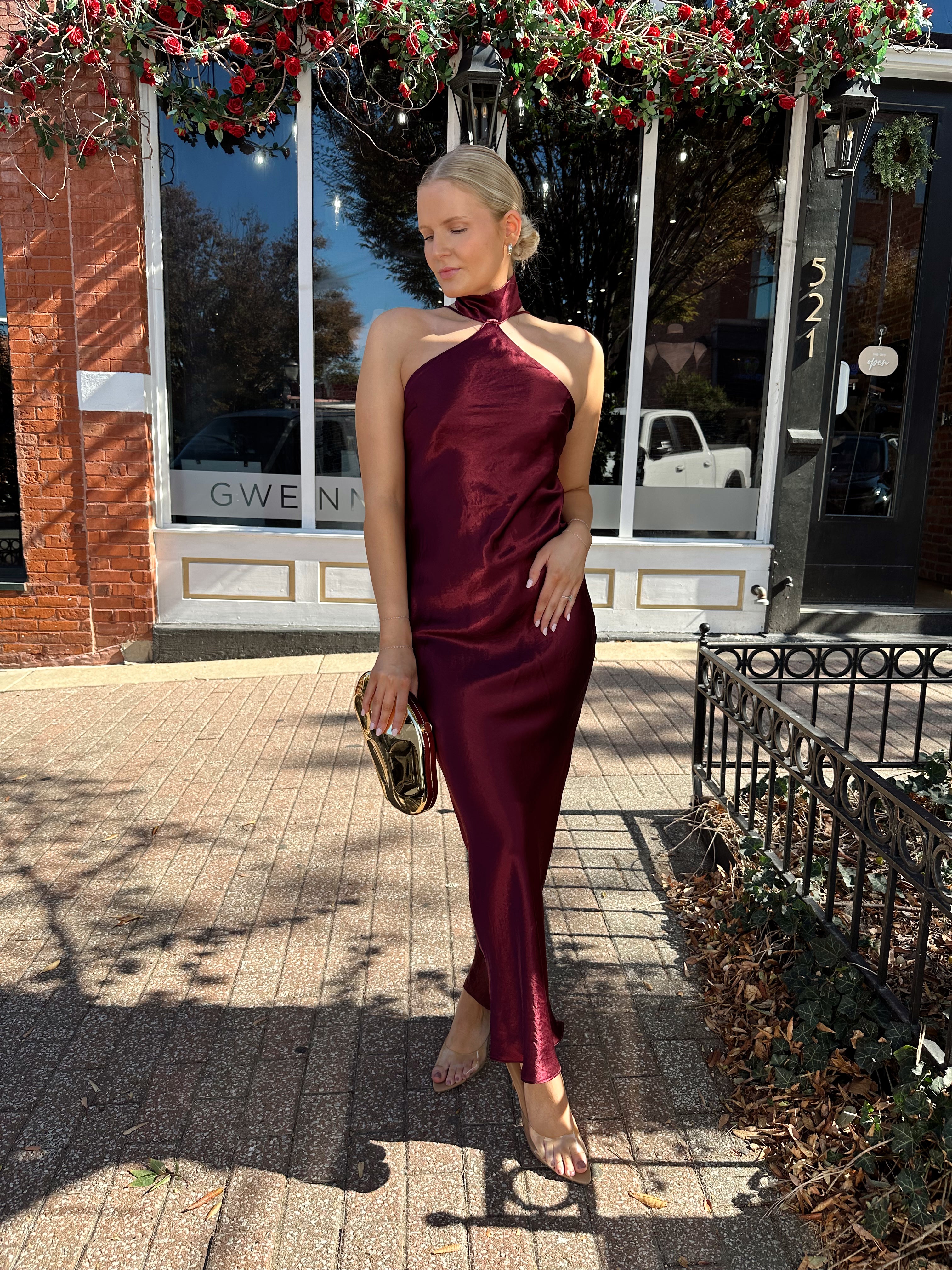 Woman wearing plum satin maxi dress with halter neckline.