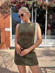 Woman wearing olive green suede mini dress with high neckline and v-back.