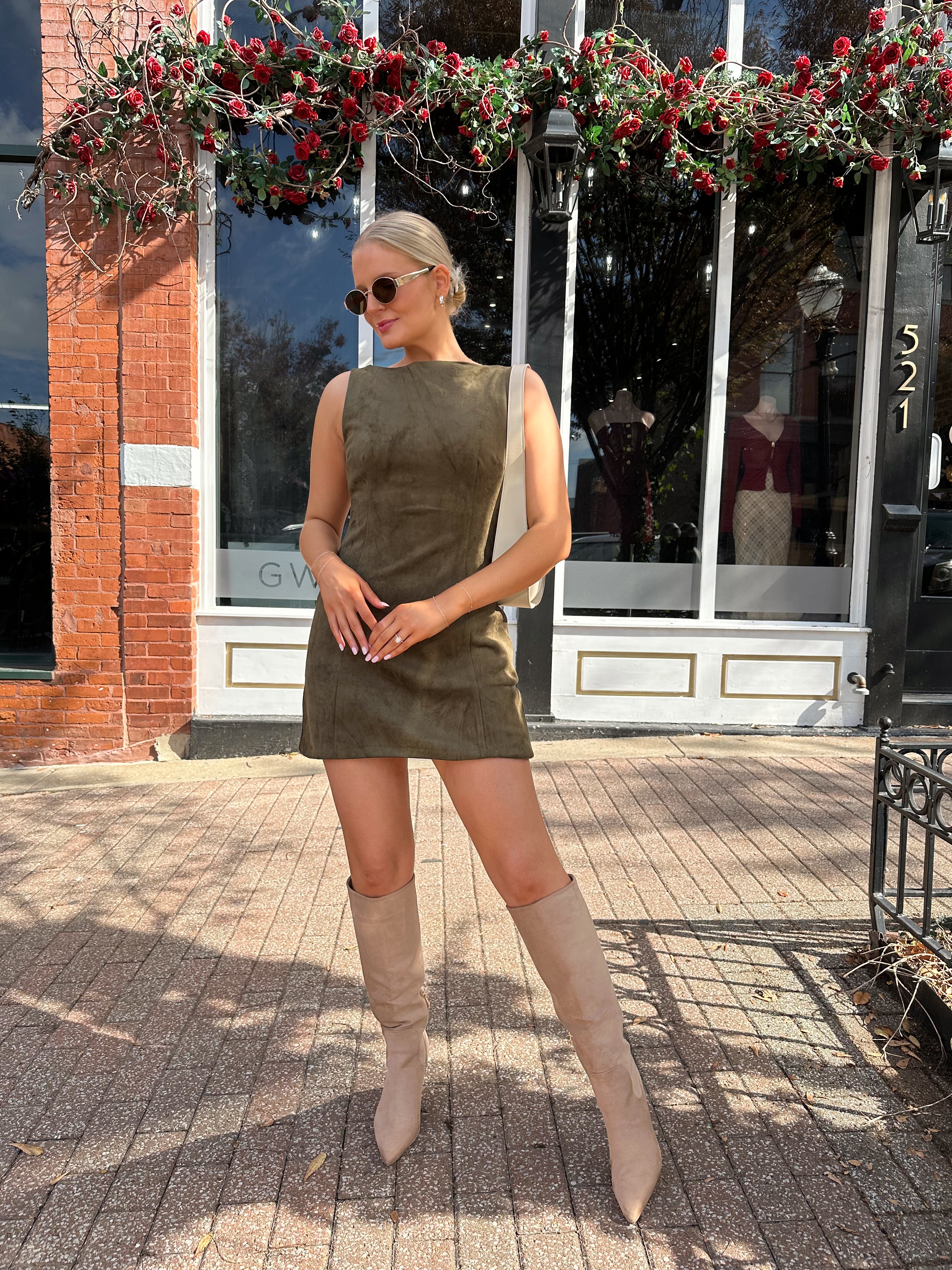 Woman wearing olive green suede mini dress with high neckline and v-back.