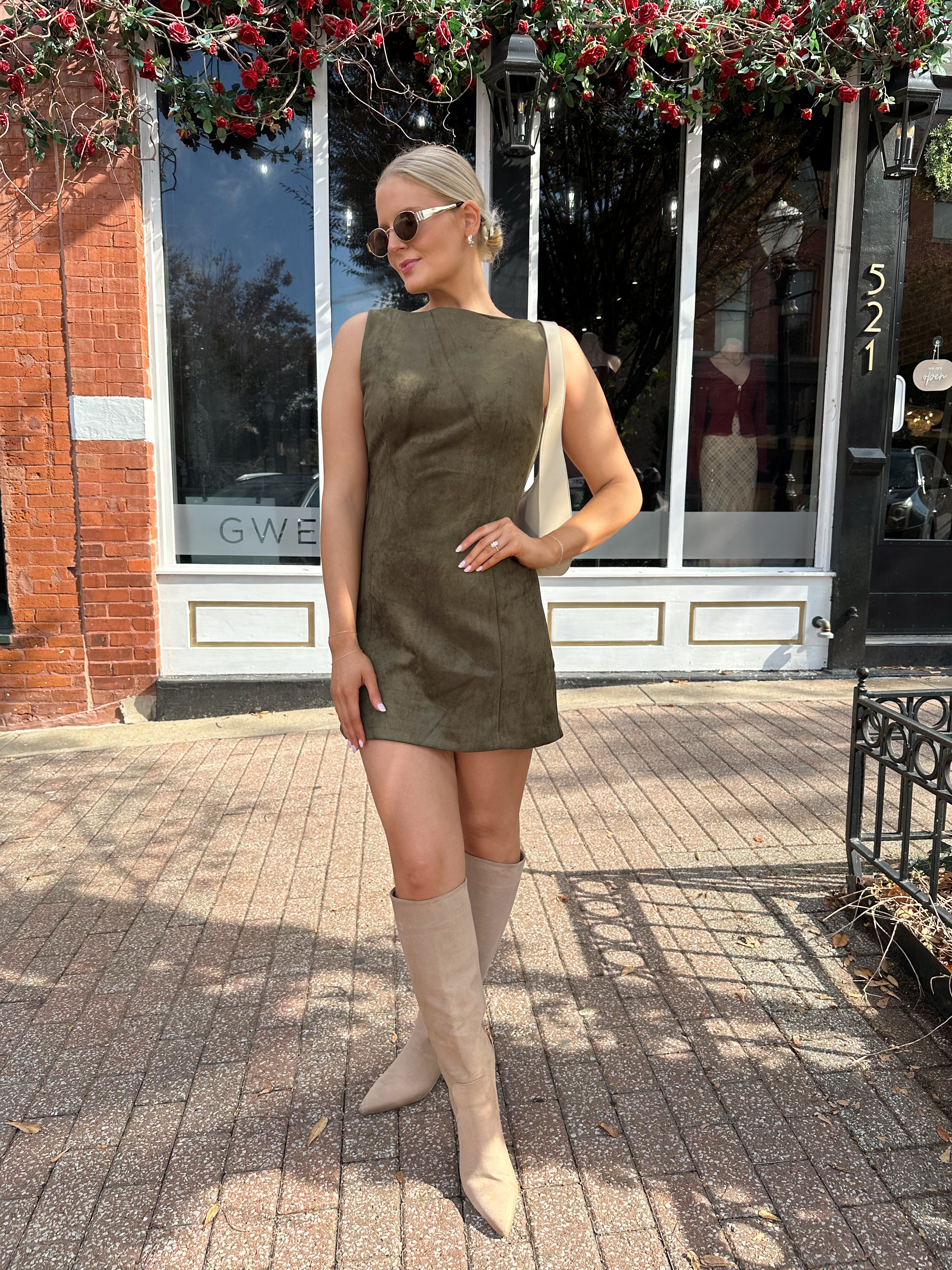 Woman wearing olive green suede mini dress with high neckline and v-back.