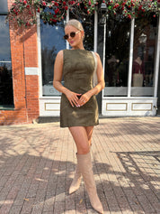 Woman wearing olive green suede mini dress with high neckline and v-back.