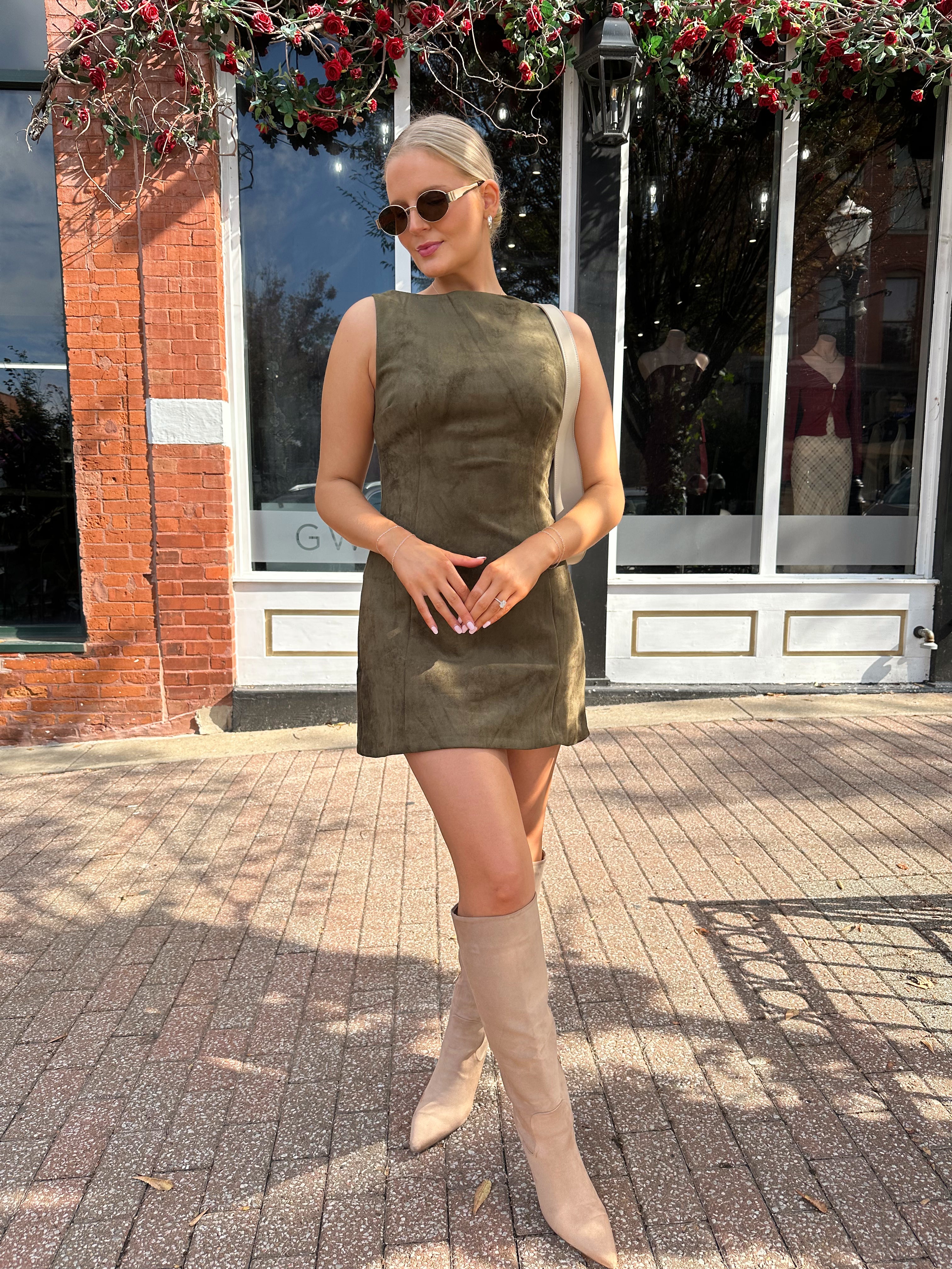 Woman wearing olive green suede mini dress with high neckline and v-back.