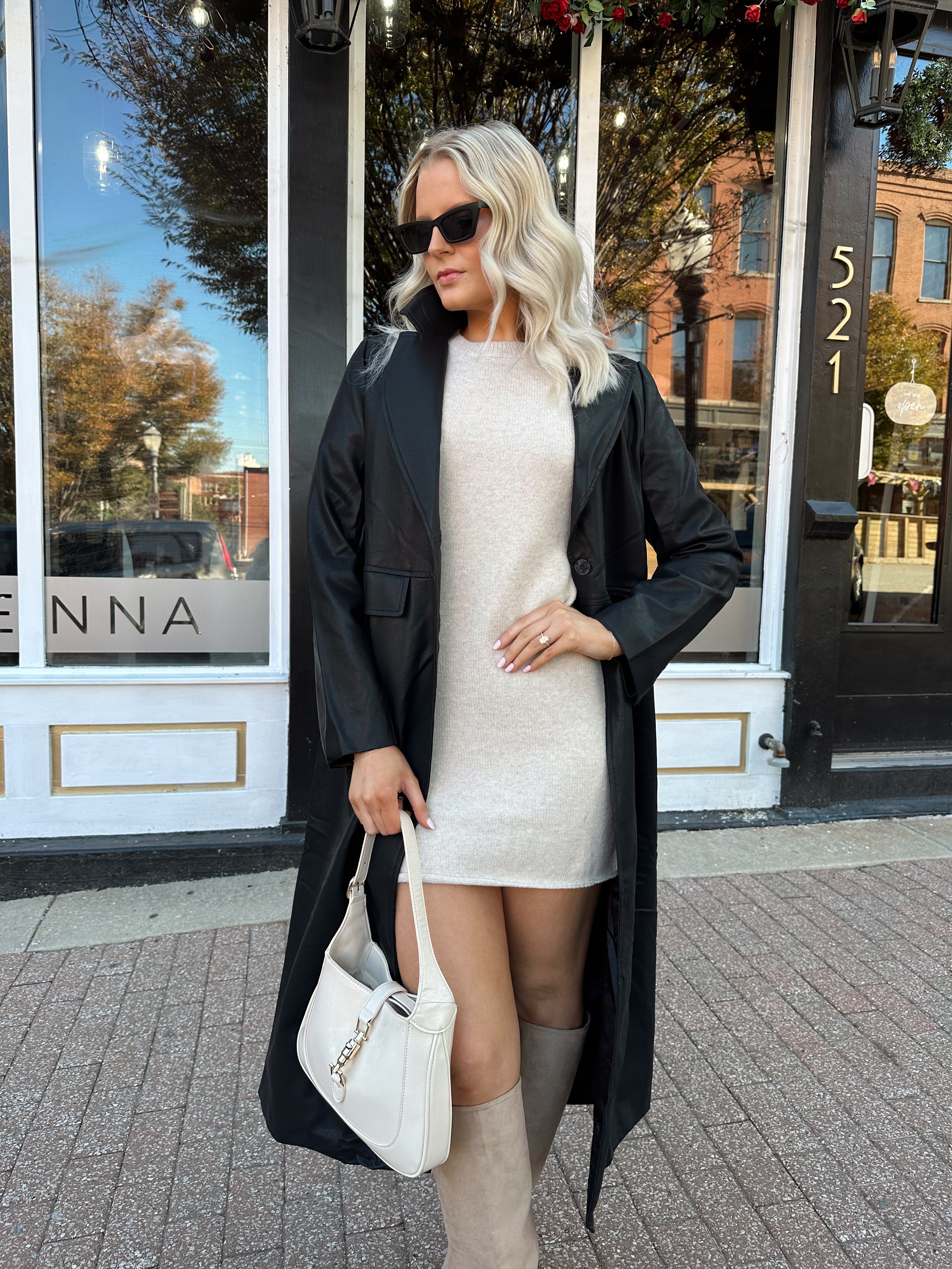 Woman wearing oatmeal knit short sleeve sweater dress and black trench coat.