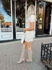 Woman wearing oatmeal knit short sleeve sweater dress and black trench coat.