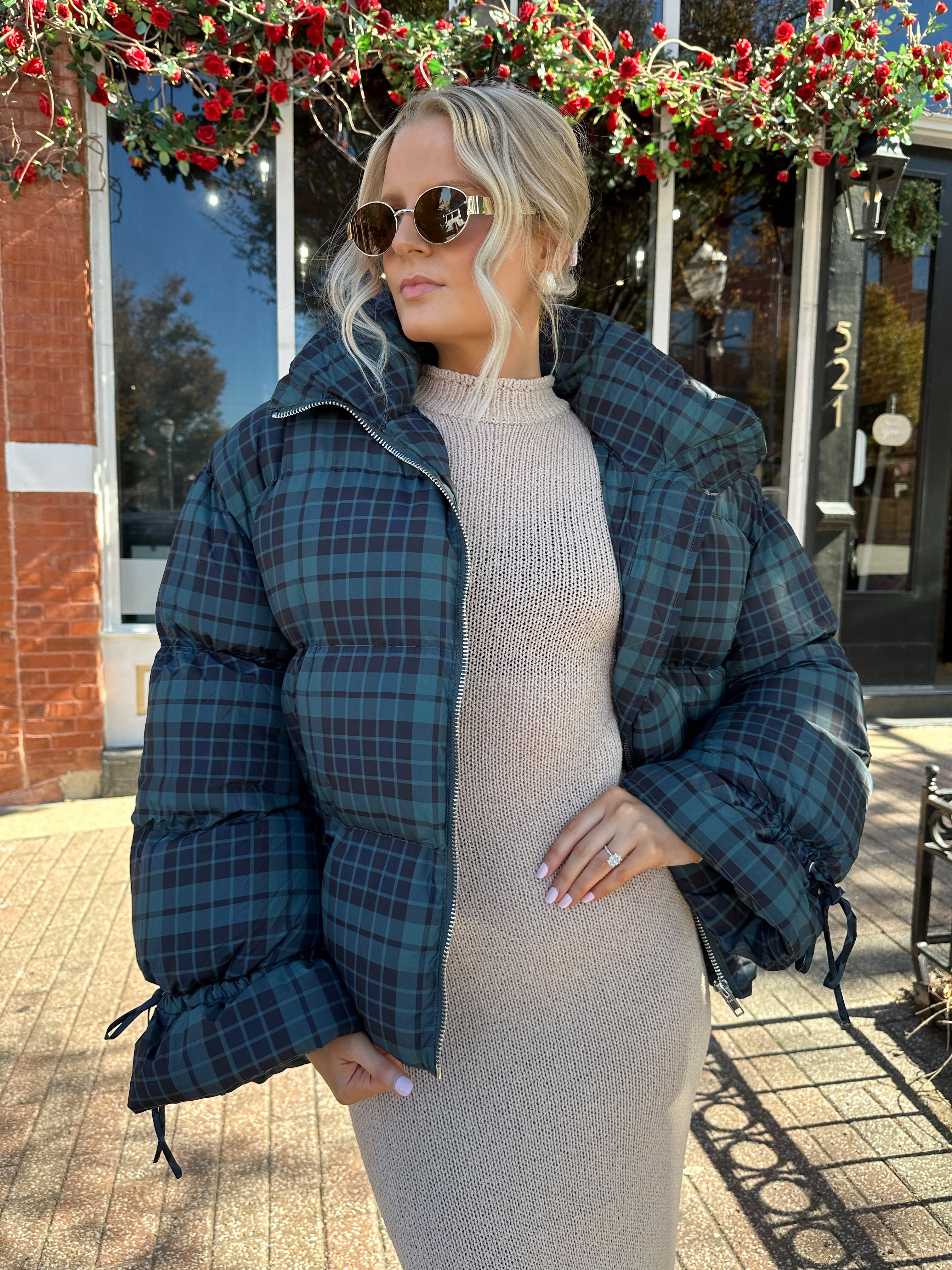Woman wearing navy plaid puffer coat with oversized fit and draw string cuffs.