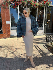 Woman wearing navy plaid puffer coat with oversized fit and draw string cuffs.