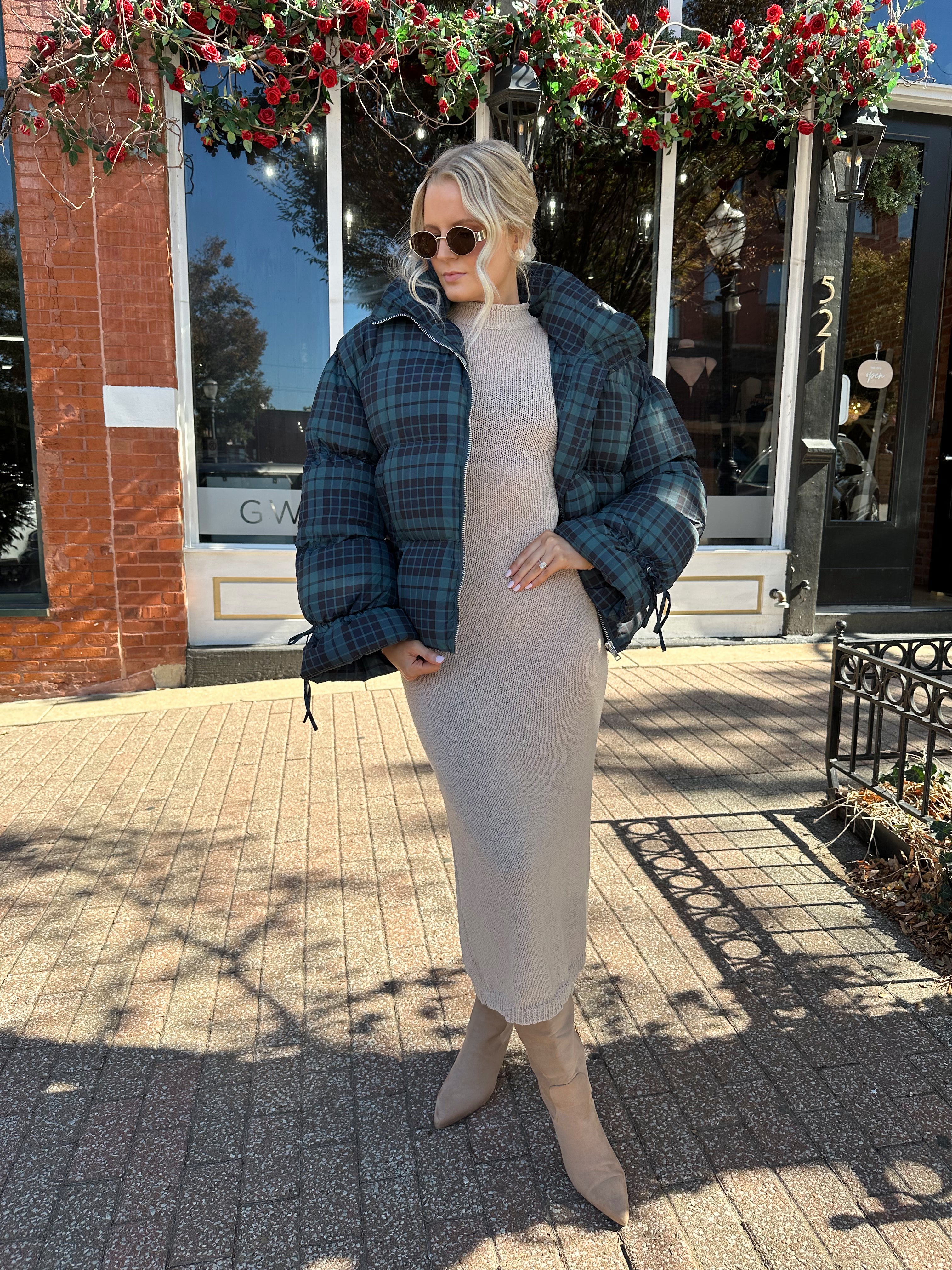 Woman wearing navy plaid puffer coat with oversized fit and draw string cuffs.