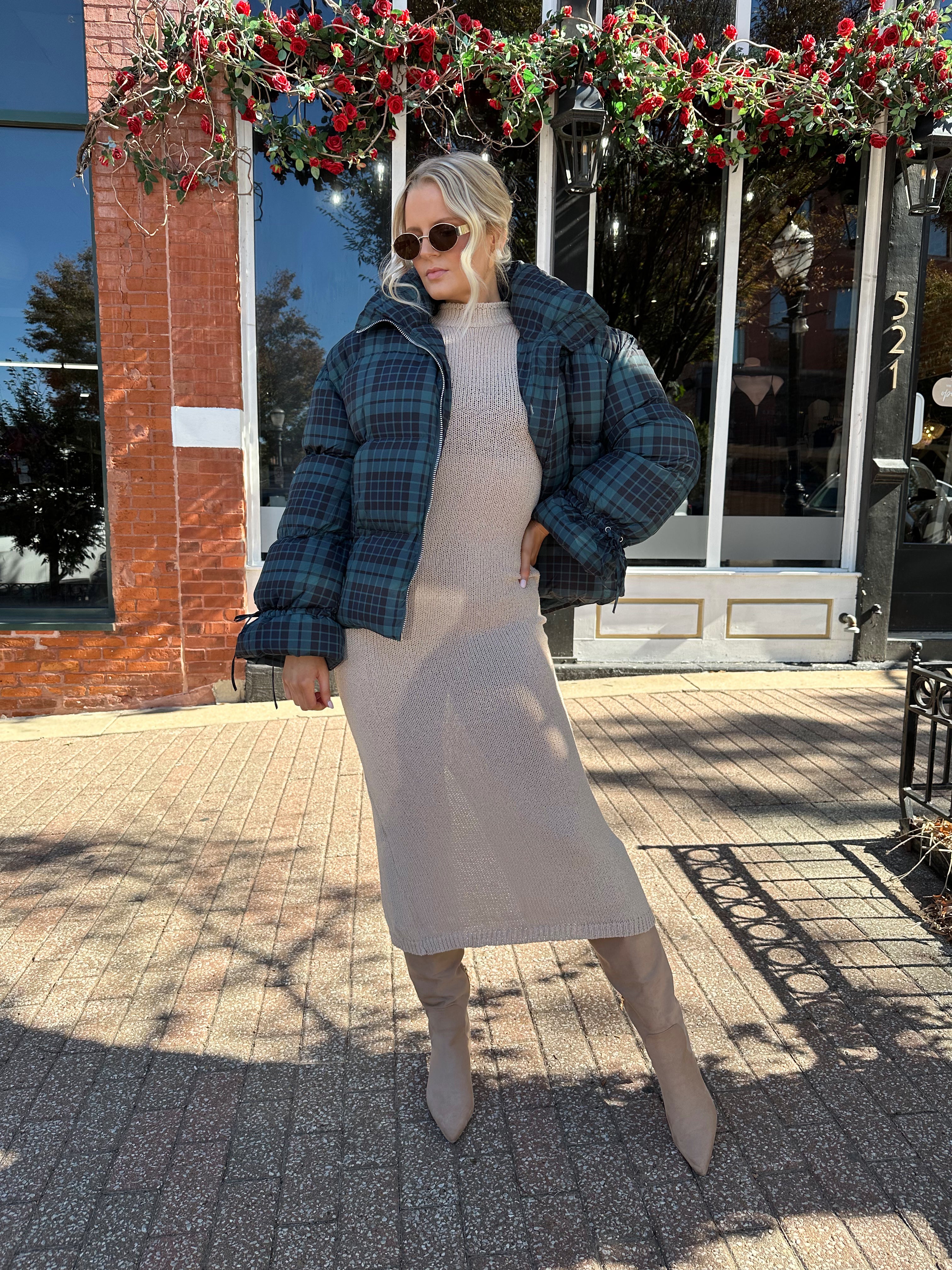 Woman wearing navy plaid puffer coat with oversized fit and draw string cuffs.