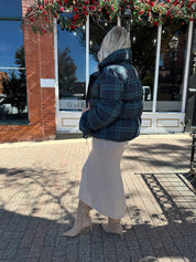 Woman wearing navy plaid puffer coat with oversized fit and draw string cuffs.