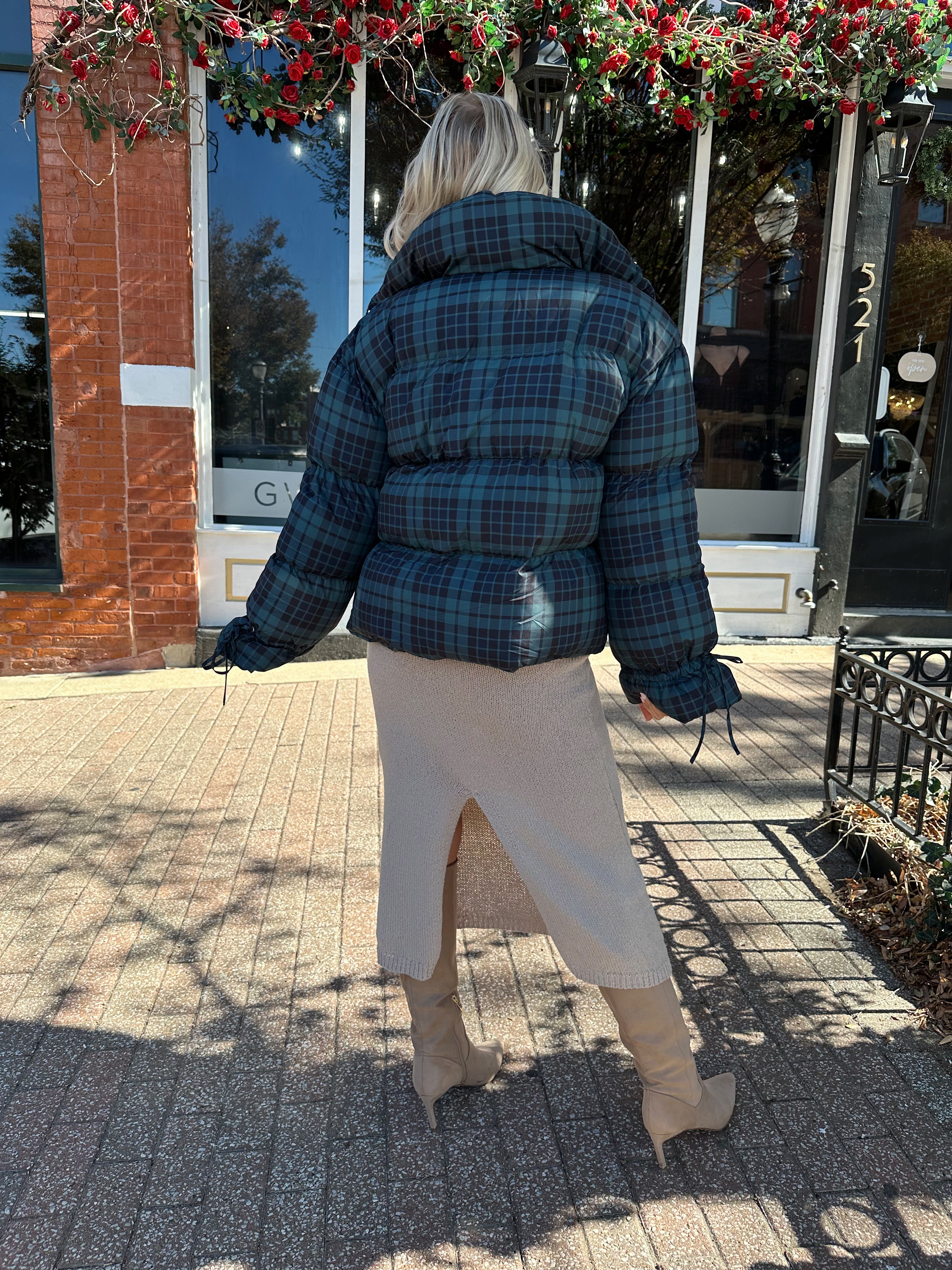 Woman wearing navy plaid puffer coat with oversized fit and draw string cuffs.