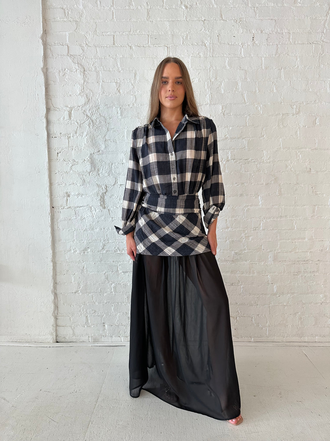 Woman wearing black checkered maxi dress with sheer maxi skirt bottom.