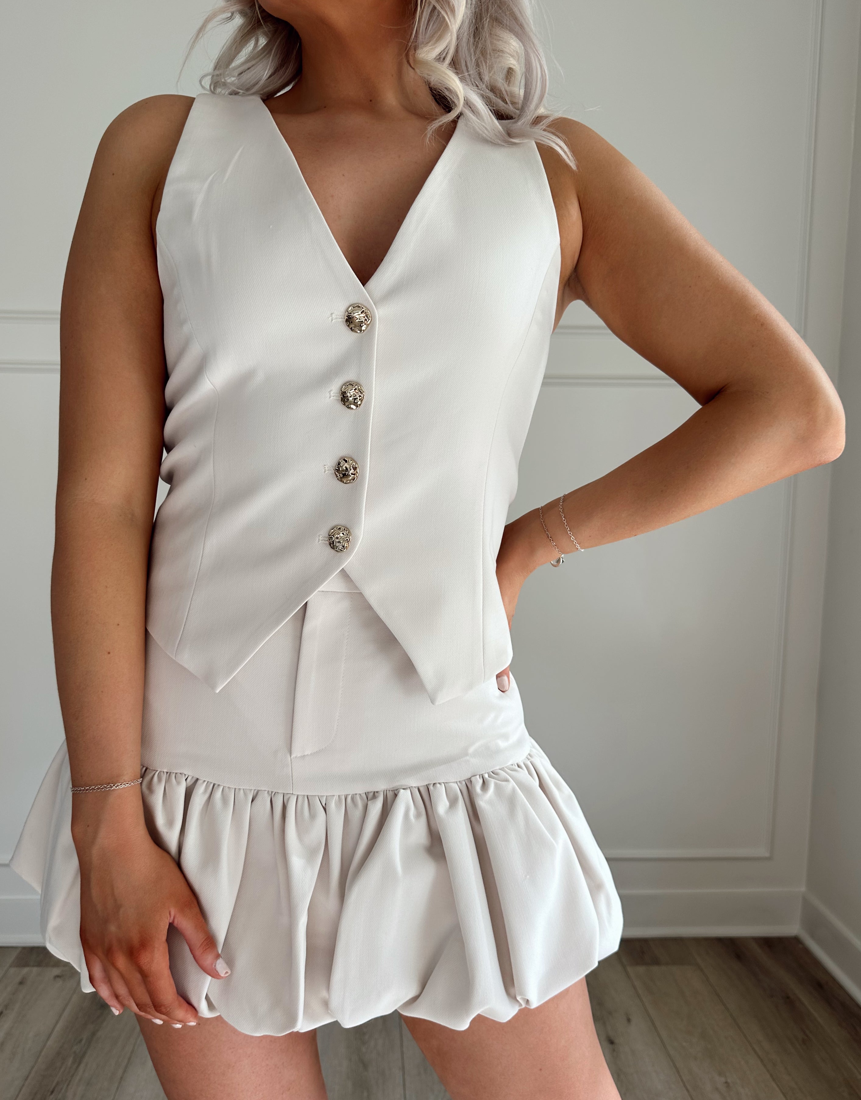 Cream tailored vest with gold button closure. 