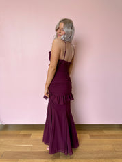 Burgundy formal maxi dress with ruffle detailing and slit up the front. 