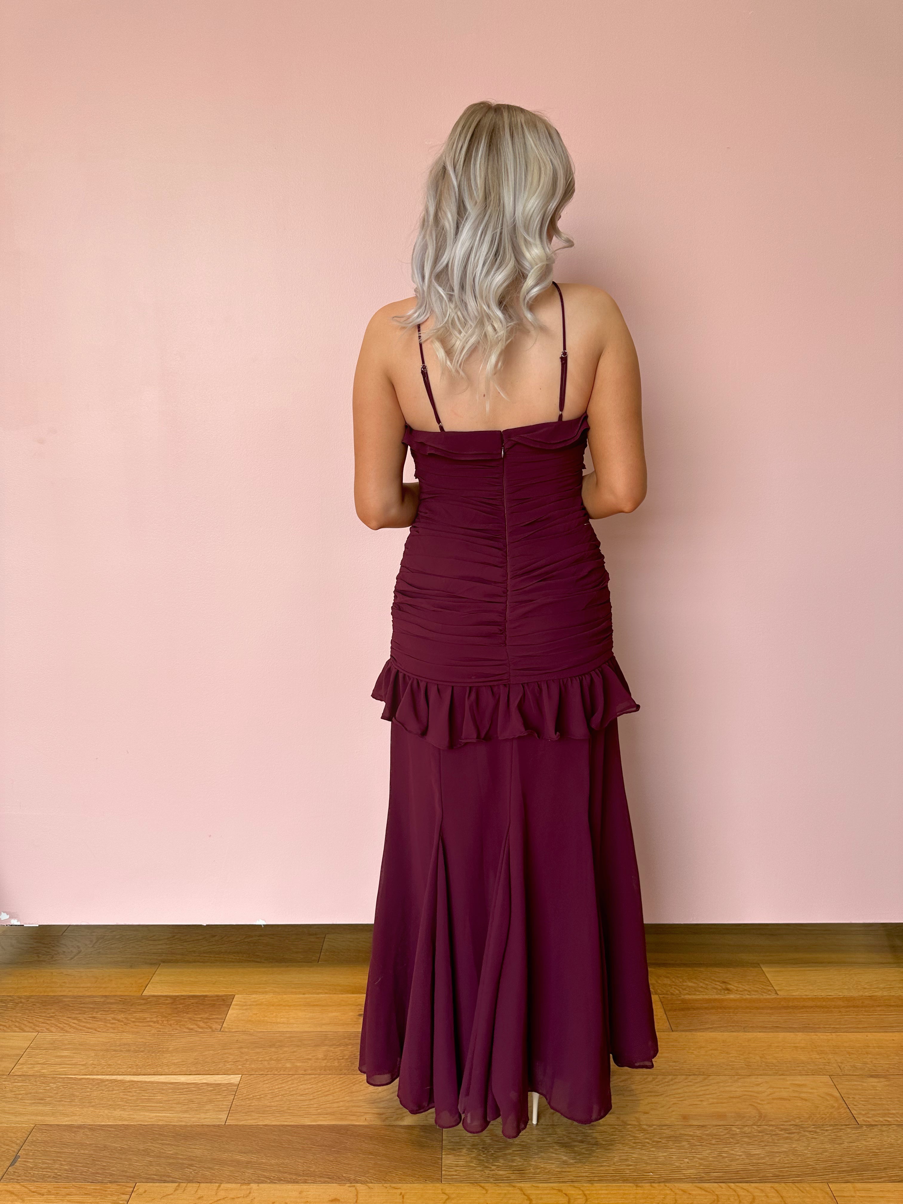 Burgundy formal maxi dress with ruffle detailing and slit up the front. 