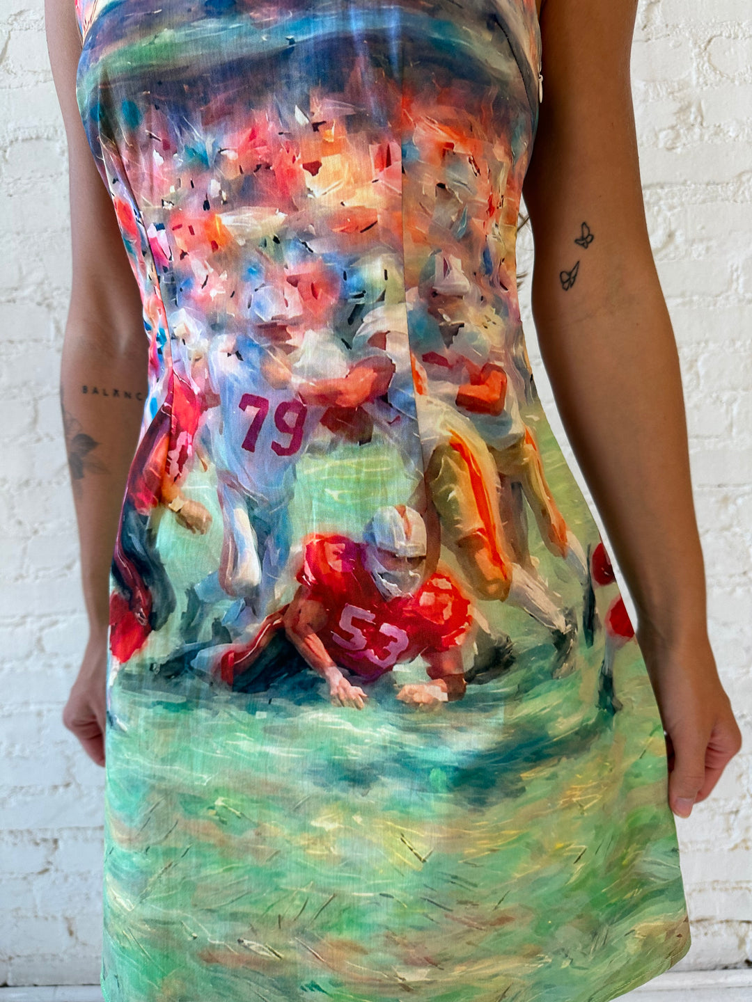Woman wearing abstract football a-line style mini dress with open back. 