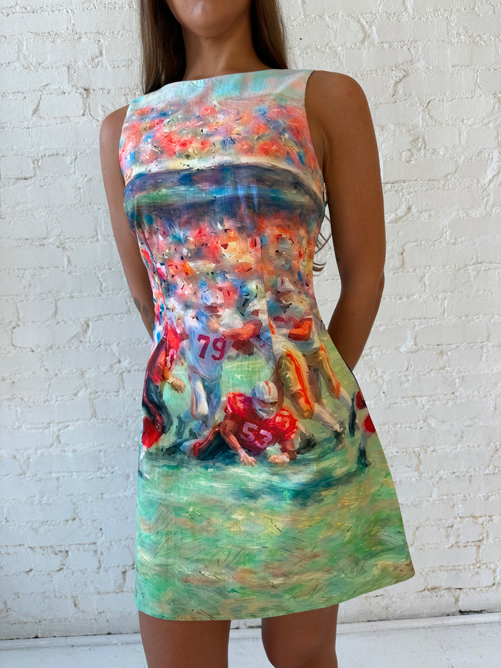 Woman wearing abstract football a-line style mini dress with open back. 
