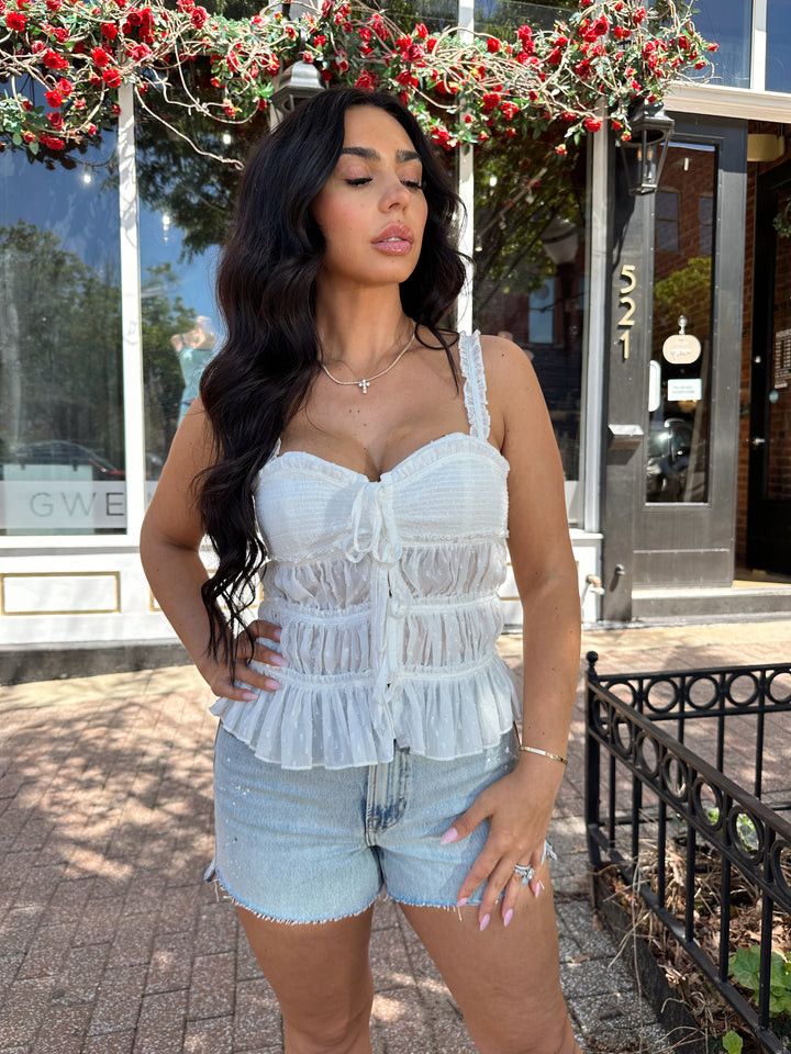 Woman wearing light wash, high waisted denim short with raw hem.