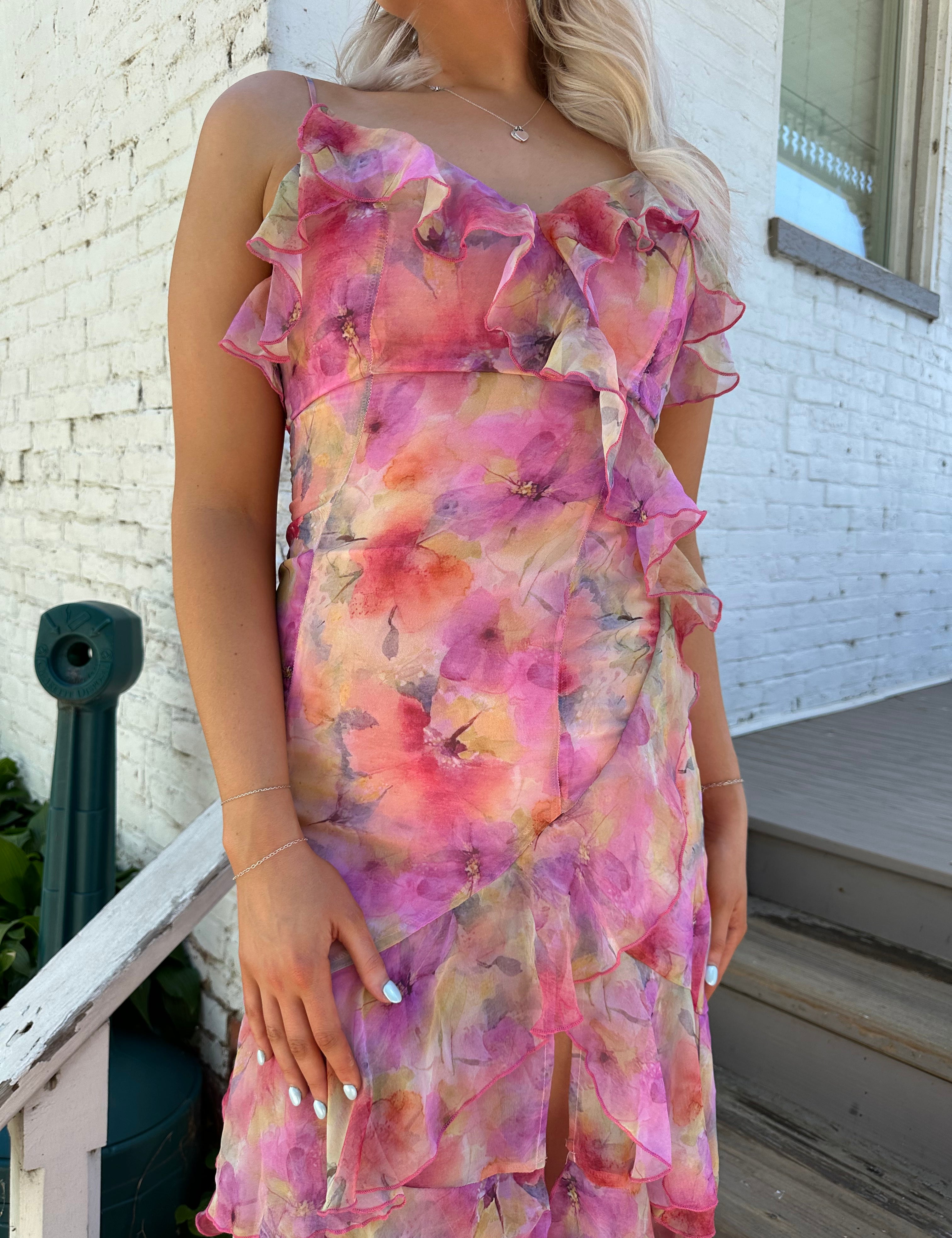 Woman wearing a pink and yellow floral tiered midi dress with ruffles and a front slit