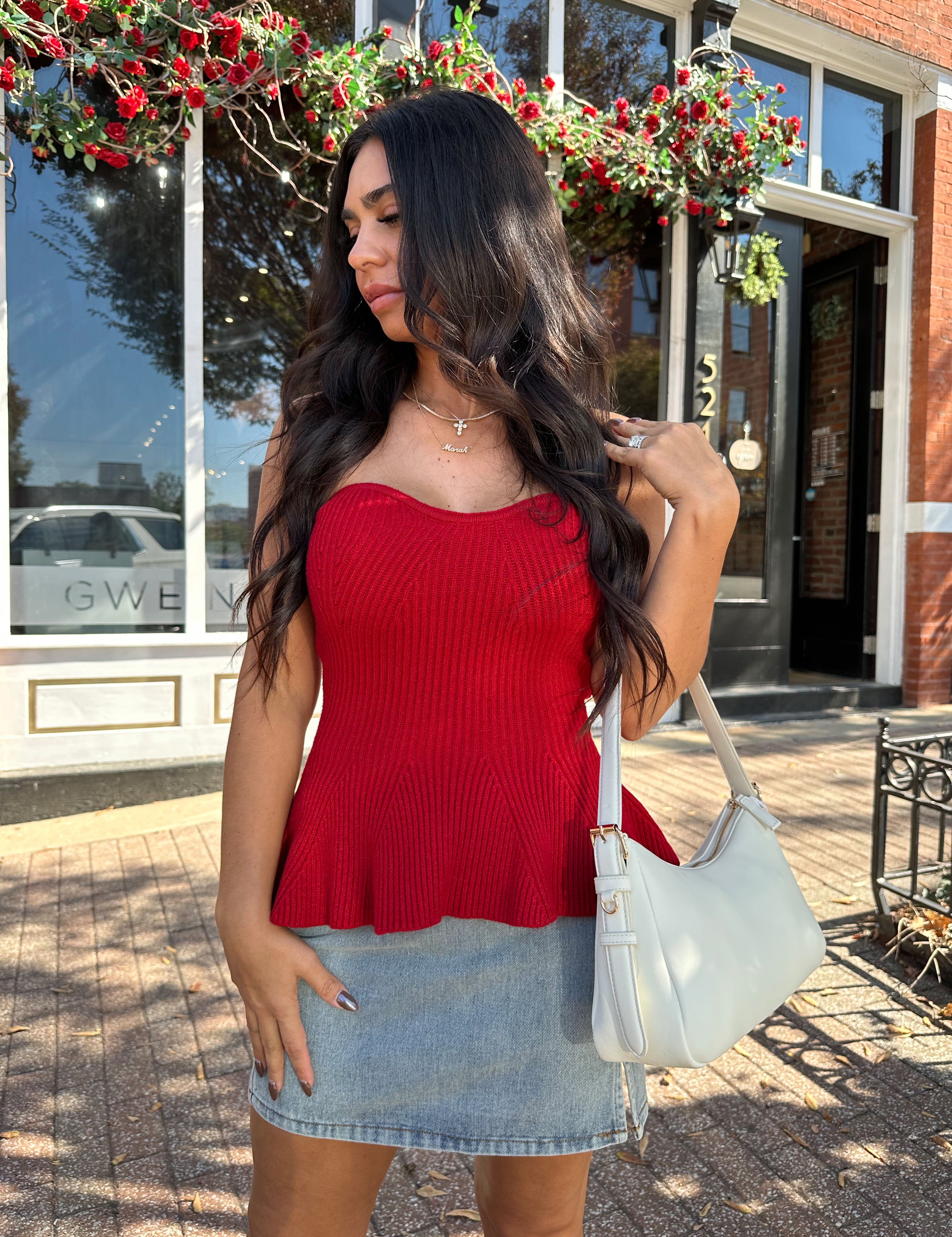 Woman wearing red strapless peplum top with denim mini skirt. 