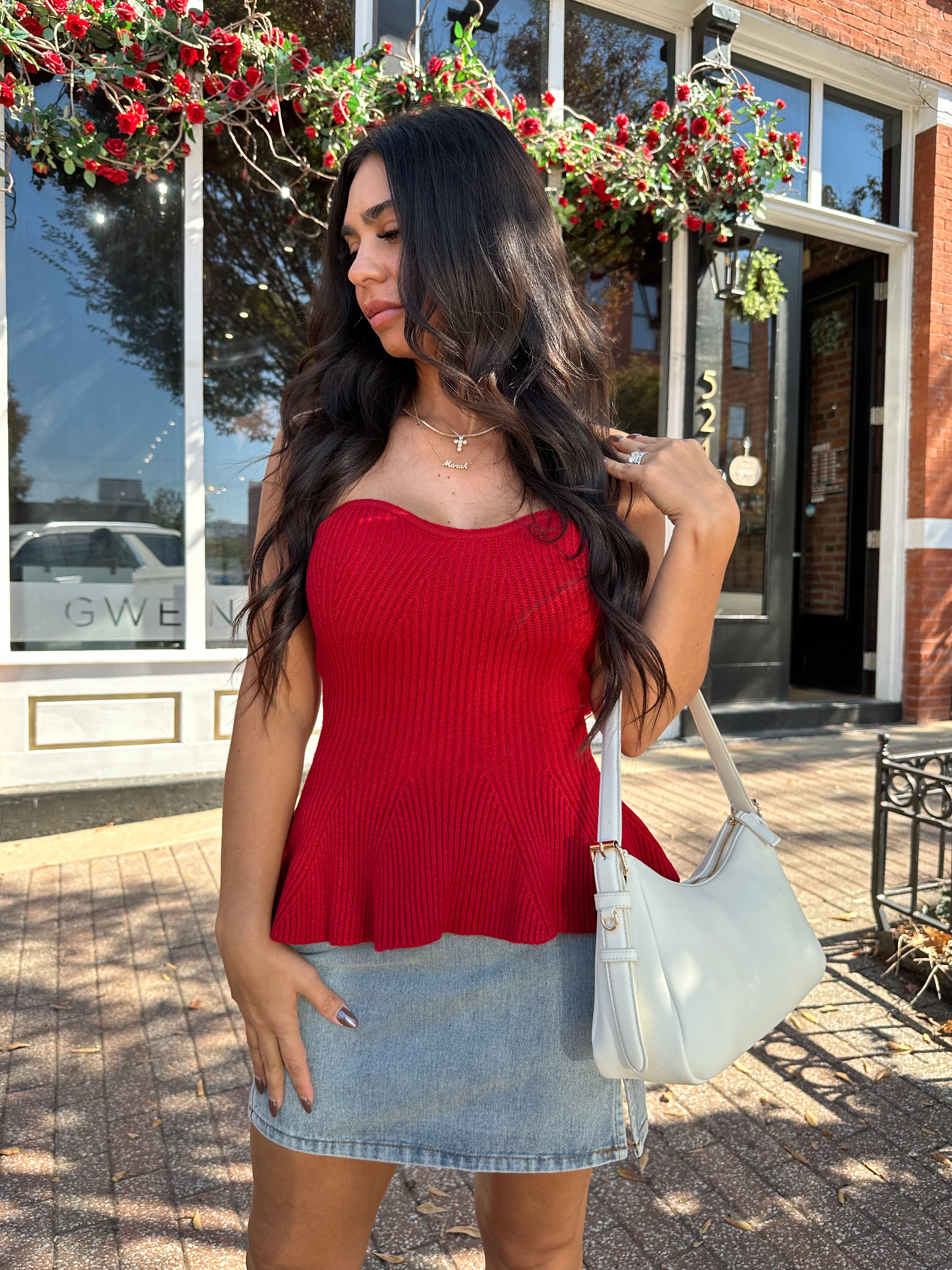 Woman wearing red strapless peplum top with denim mini skirt. 