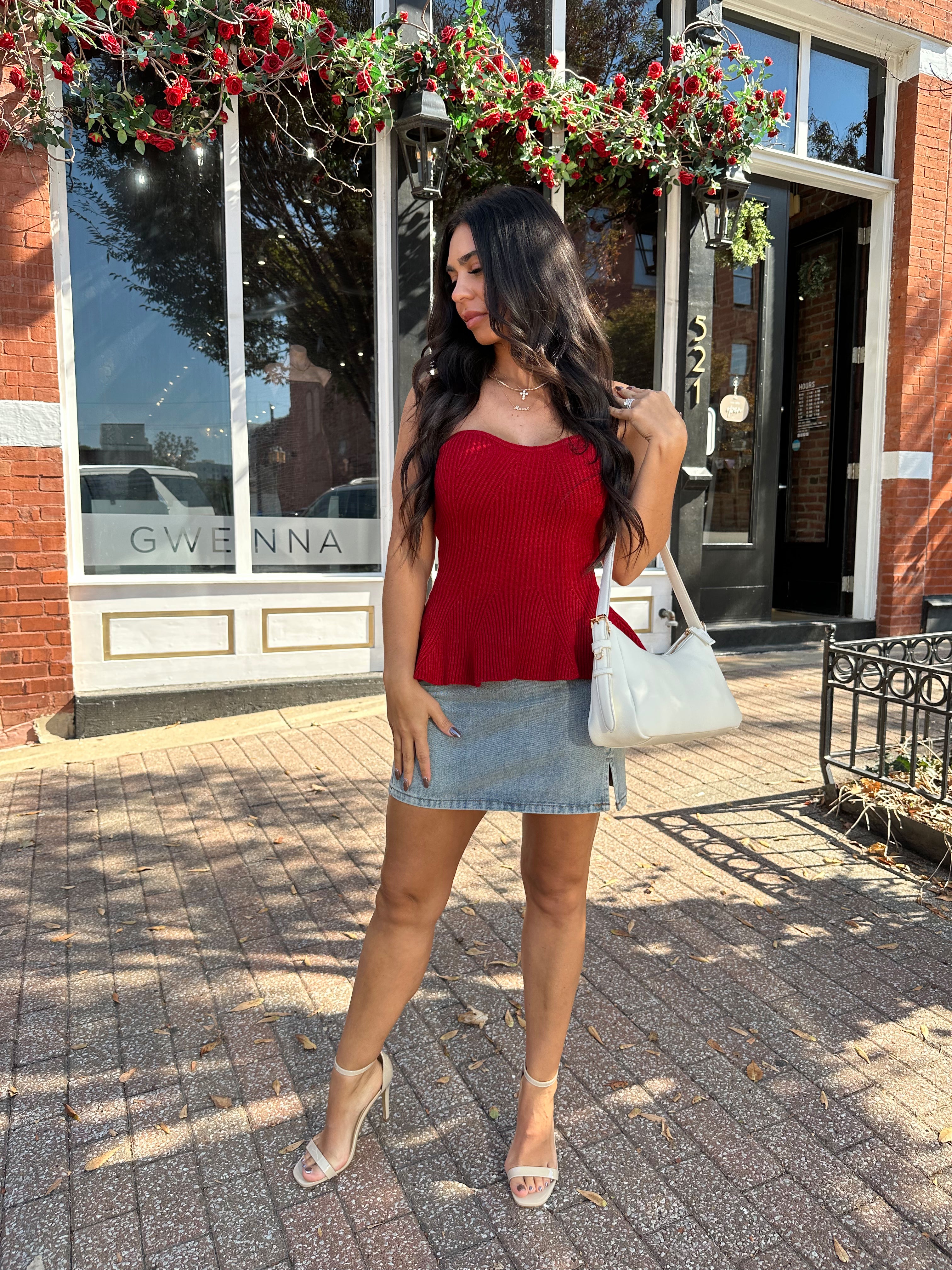 Woman wearing red strapless peplum top with denim mini skirt. 