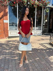 Woman wearing red strapless peplum top with denim mini skirt. 