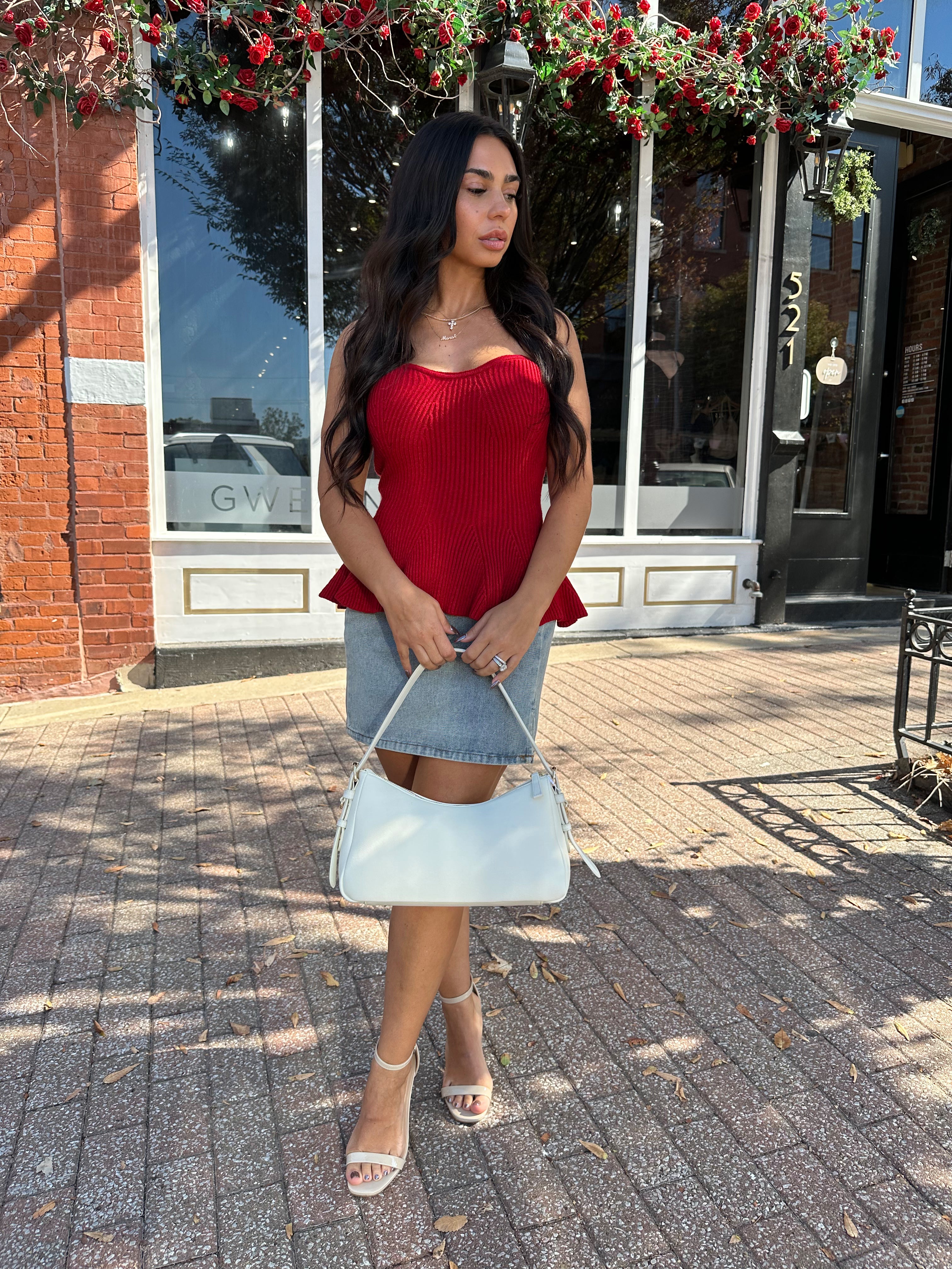 Woman wearing red strapless peplum top with denim mini skirt. 