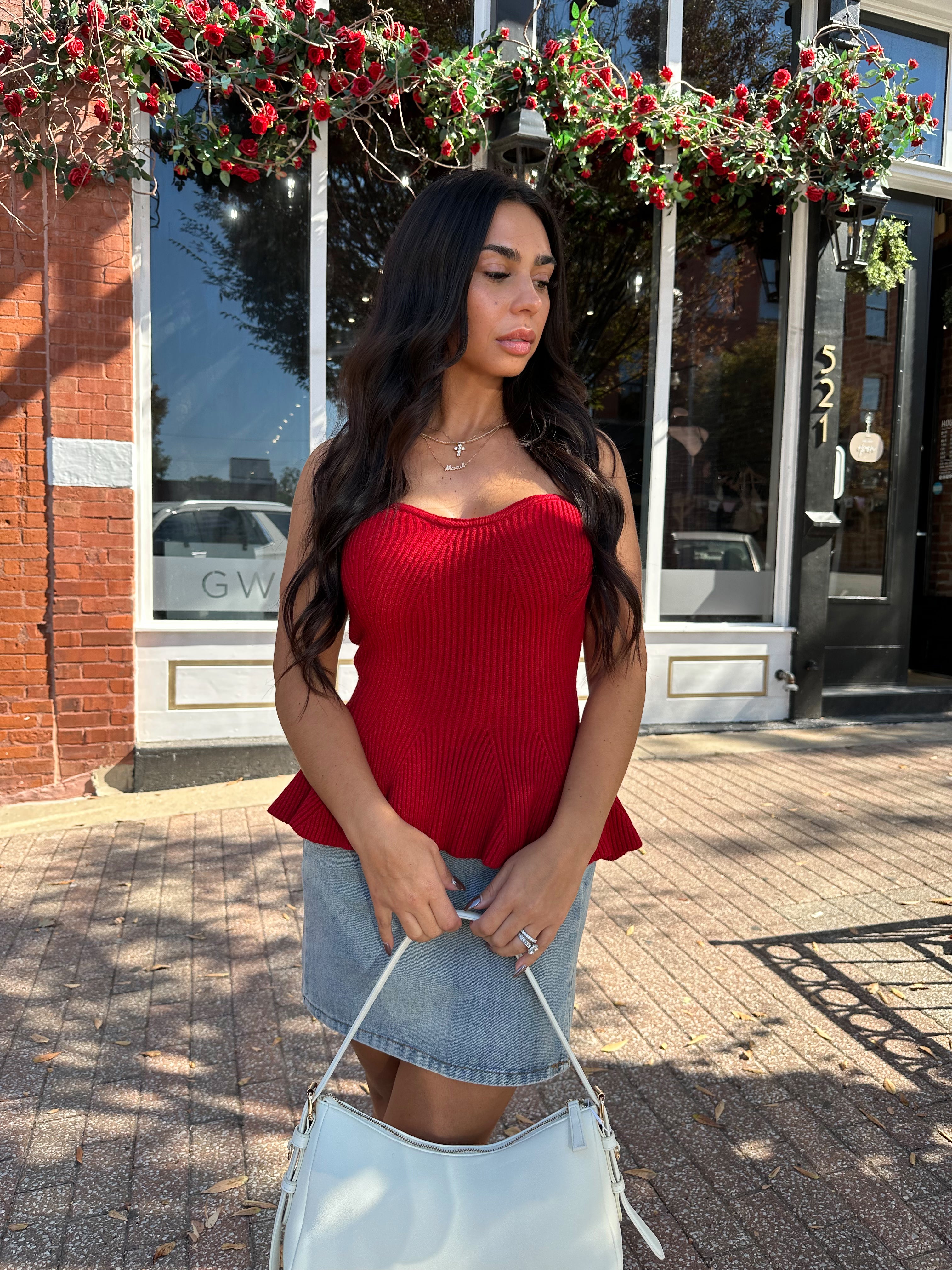 Woman wearing red strapless peplum top with denim mini skirt. 