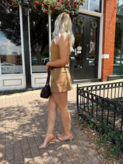 Woman wearing tan suede strapless corset top with suede mini skirt.