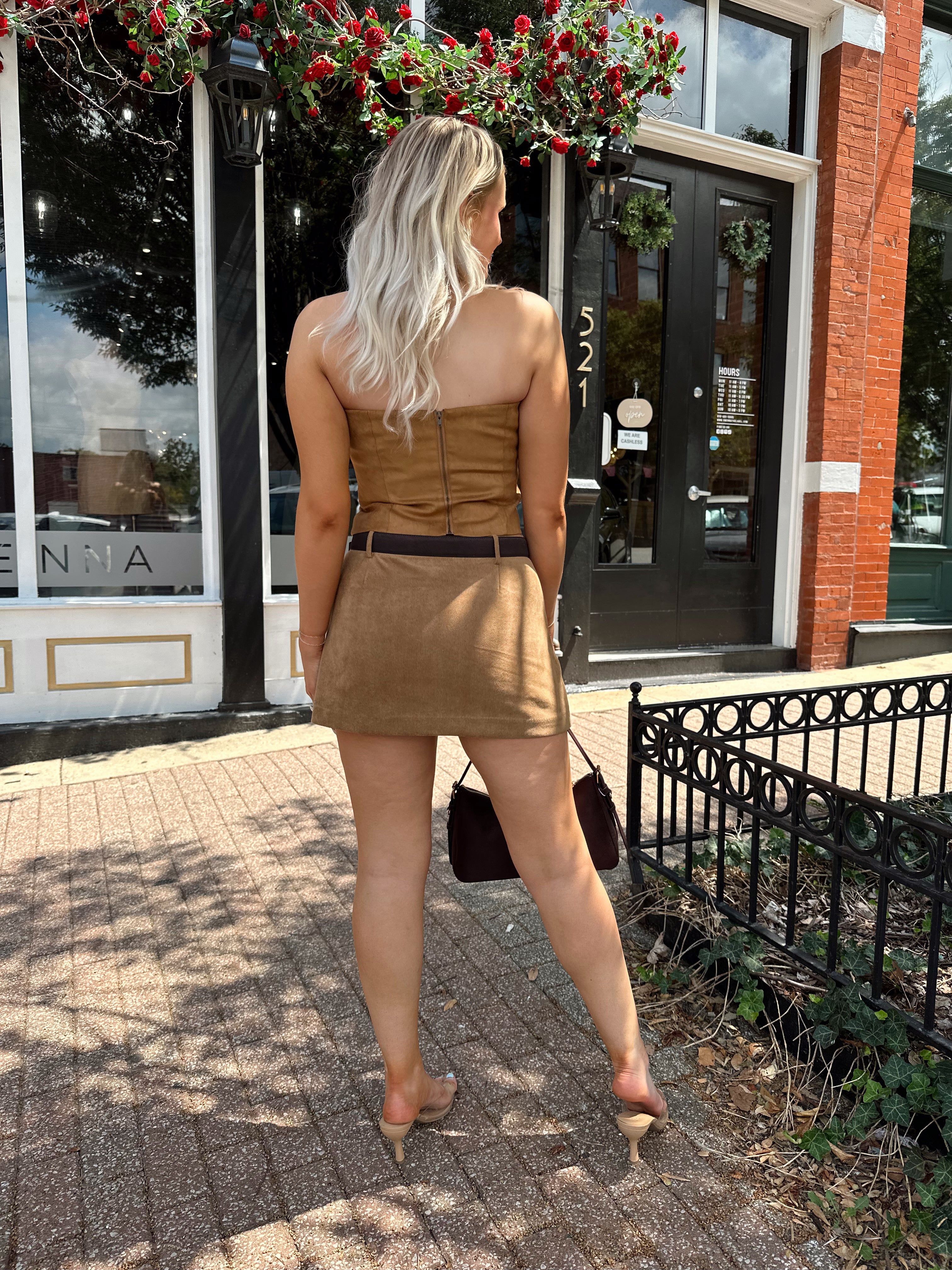 Woman wearing tan suede strapless corset top with suede mini skirt.
