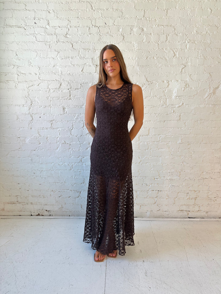 Woman wearing high neck, dark brown lace maxi dress with solid mini dress underlay.