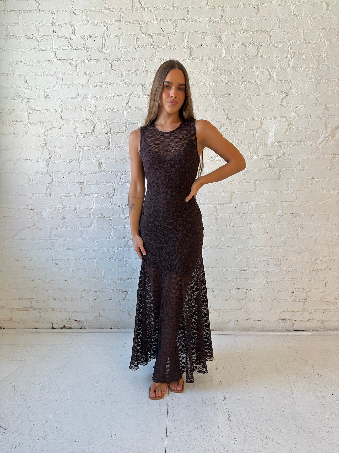 Woman wearing high neck, dark brown lace maxi dress with solid mini dress underlay.
