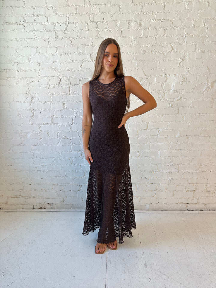 Woman wearing high neck, dark brown lace maxi dress with solid mini dress underlay.