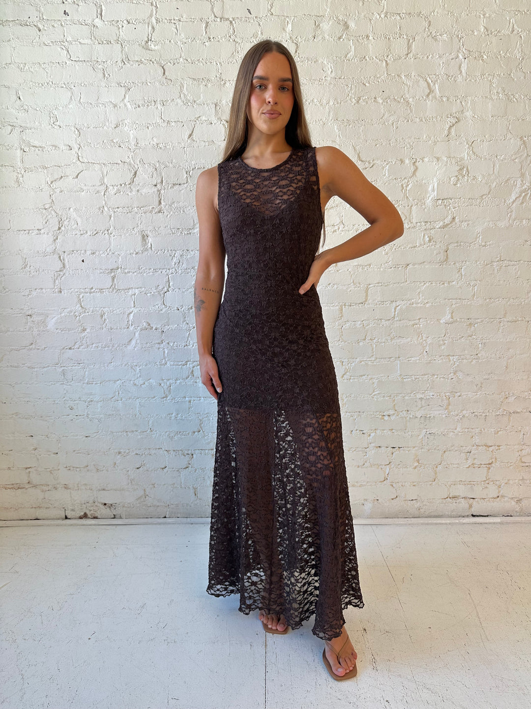 Woman wearing high neck, dark brown lace maxi dress with solid mini dress underlay.