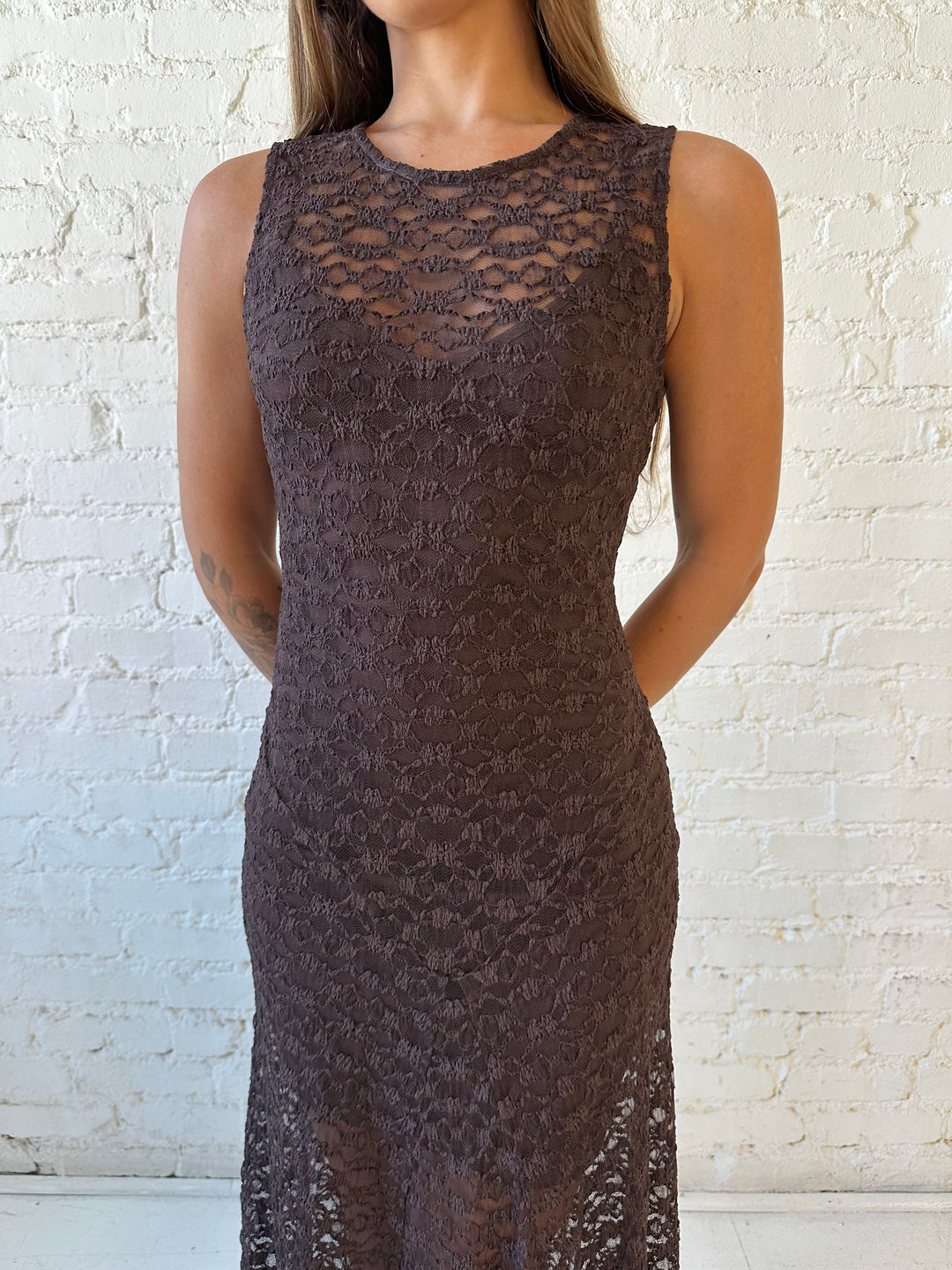 Woman wearing high neck, dark brown lace maxi dress with solid mini dress underlay.