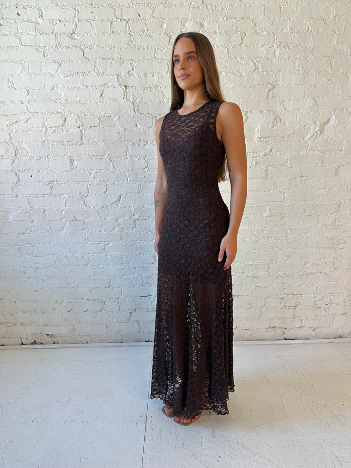 Woman wearing high neck, dark brown lace maxi dress with solid mini dress underlay.