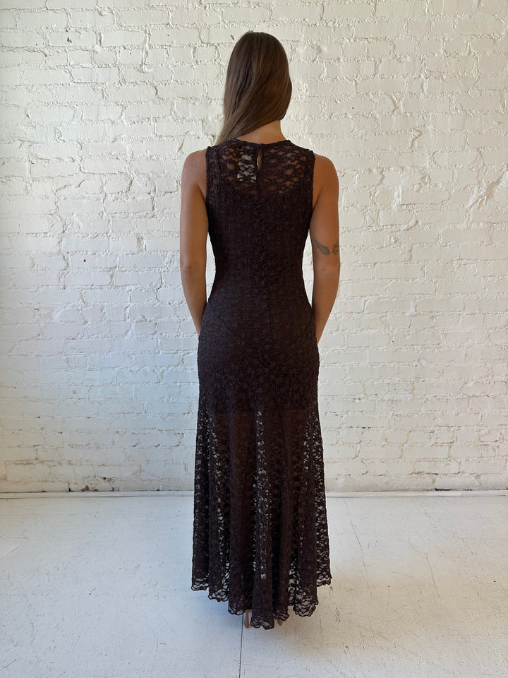 Woman wearing high neck, dark brown lace maxi dress with solid mini dress underlay.
