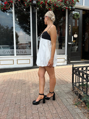 Woman wearing color block bubble mini dress with keyhole cutout and tie detail.