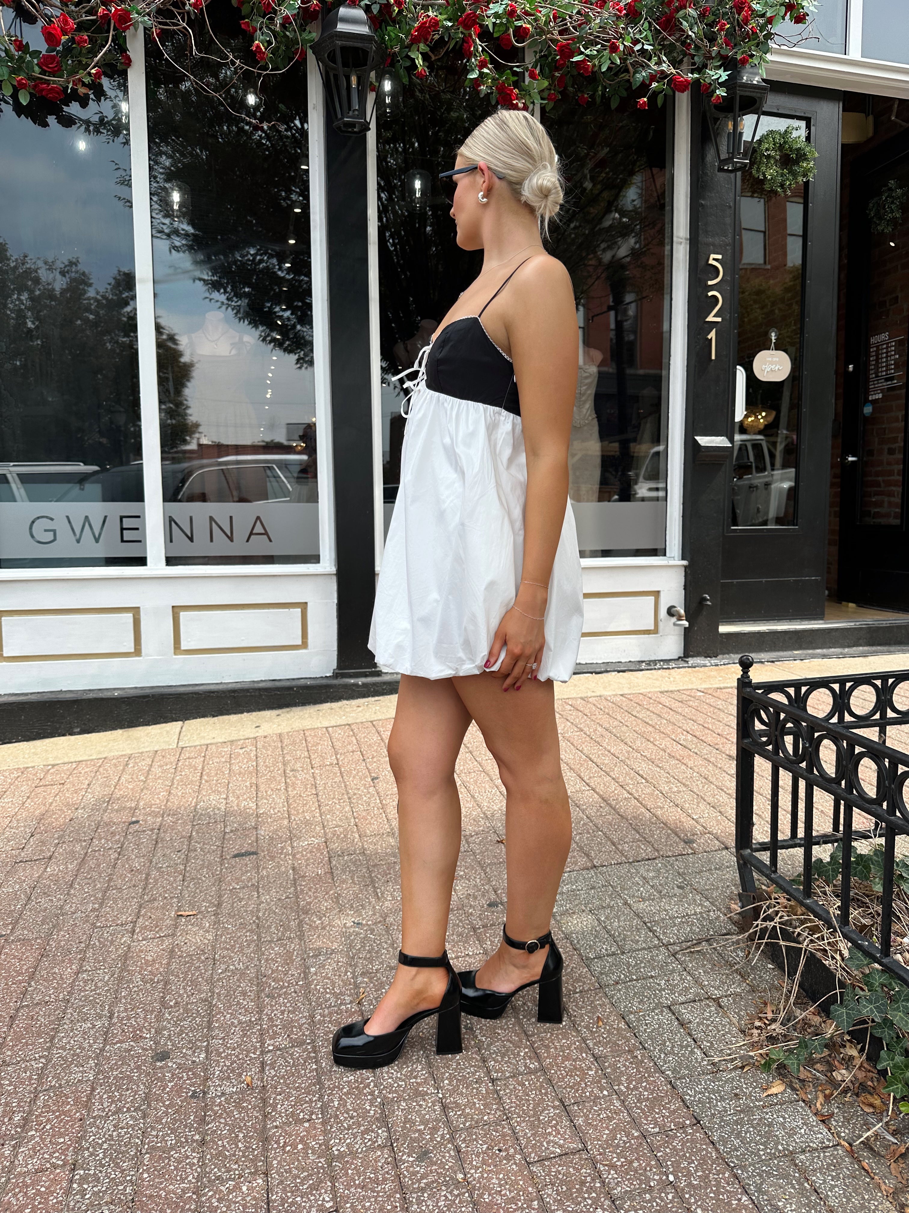 Woman wearing color block bubble mini dress with keyhole cutout and tie detail.