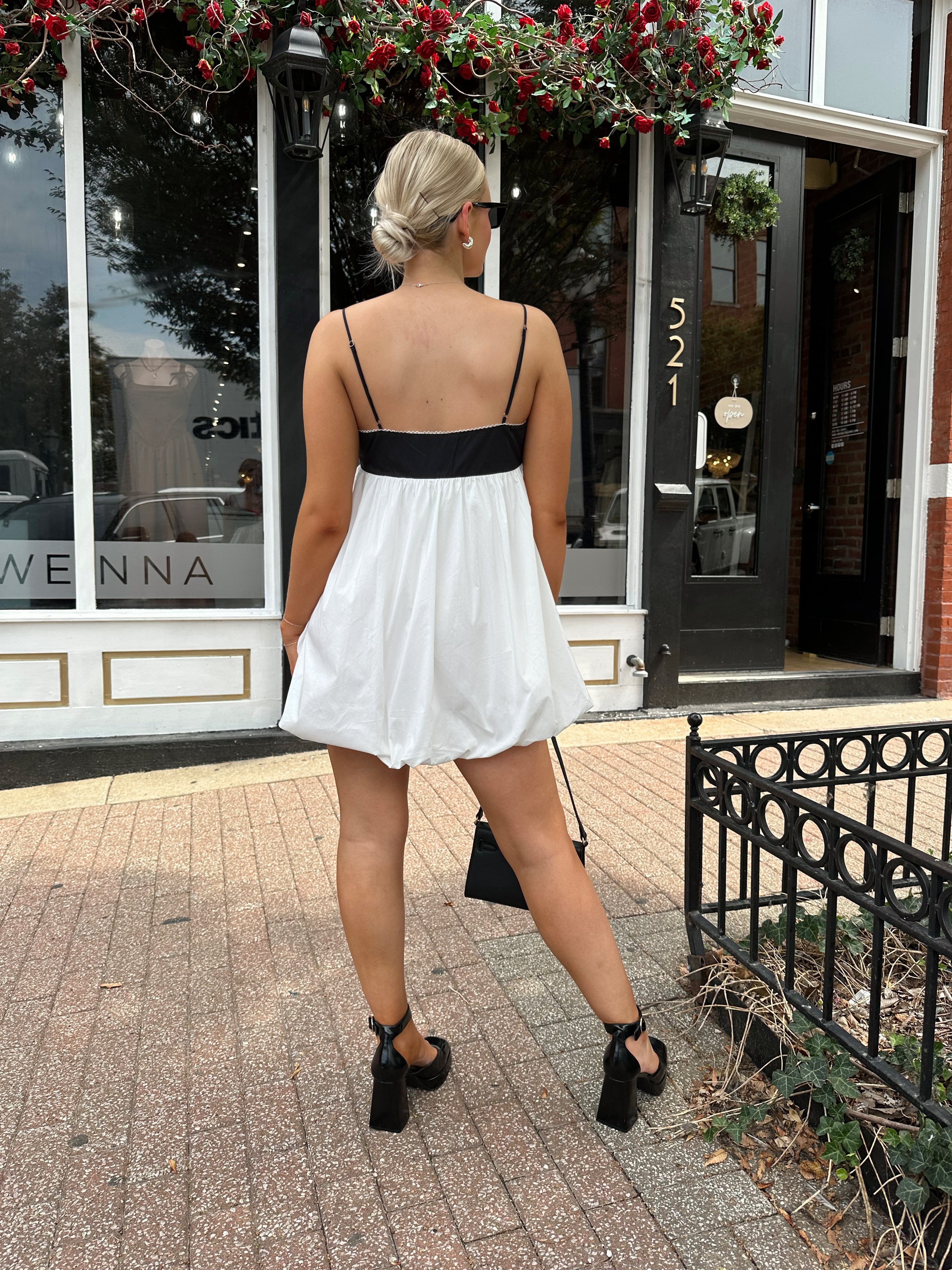 Woman wearing color block bubble mini dress with keyhole cutout and tie detail.