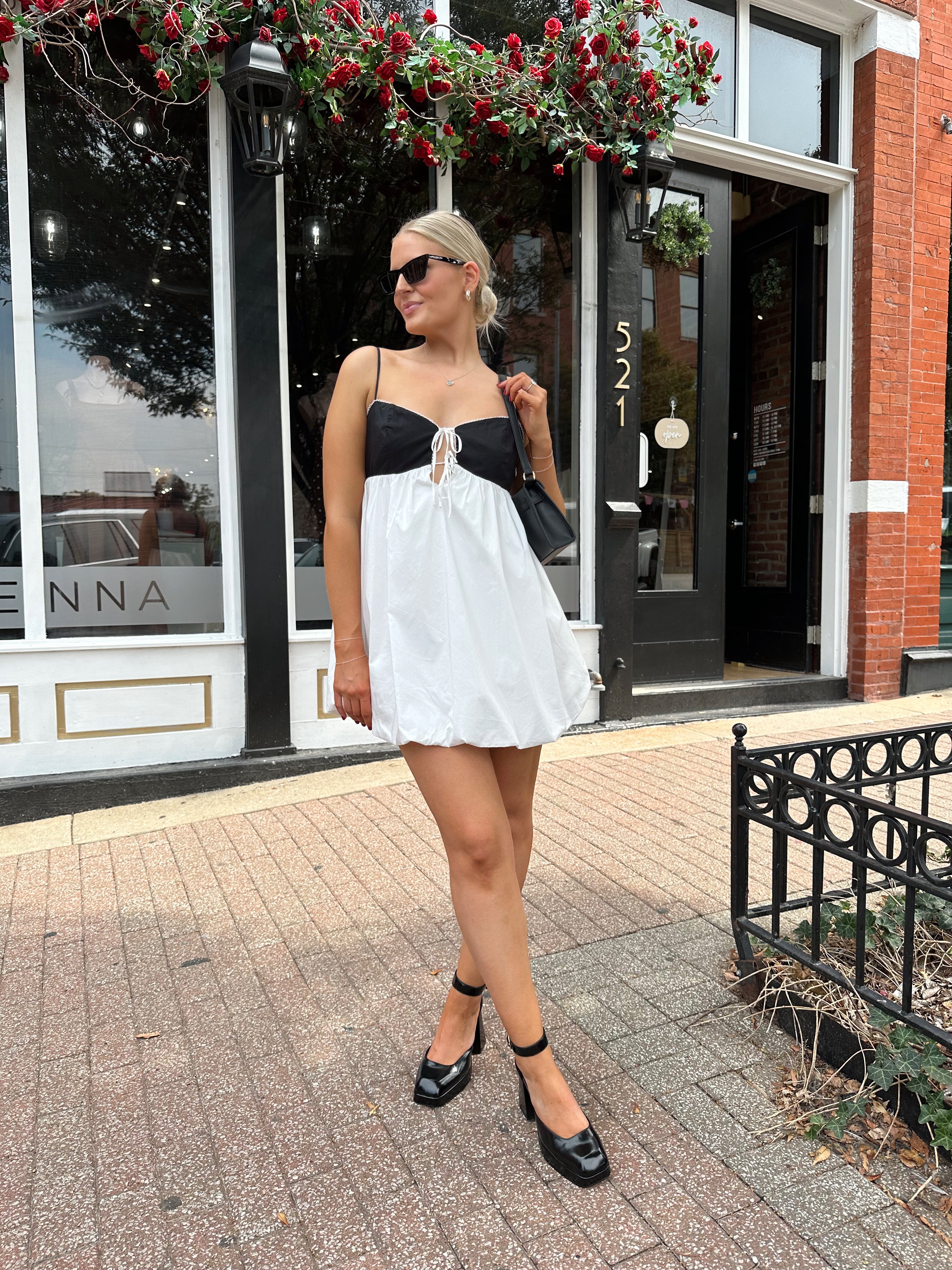 Woman wearing color block bubble mini dress with keyhole cutout and tie detail.