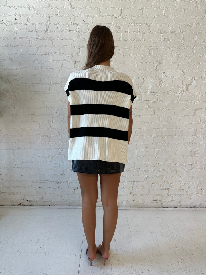 Woman wearing black and white chunky oversized sweater with black faux leather skirt.
