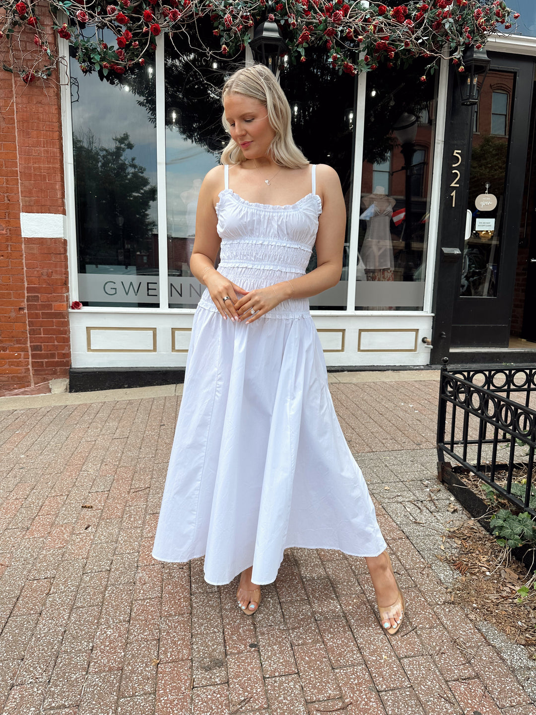 Woman wearing white smocked maxi dress with side slit. 