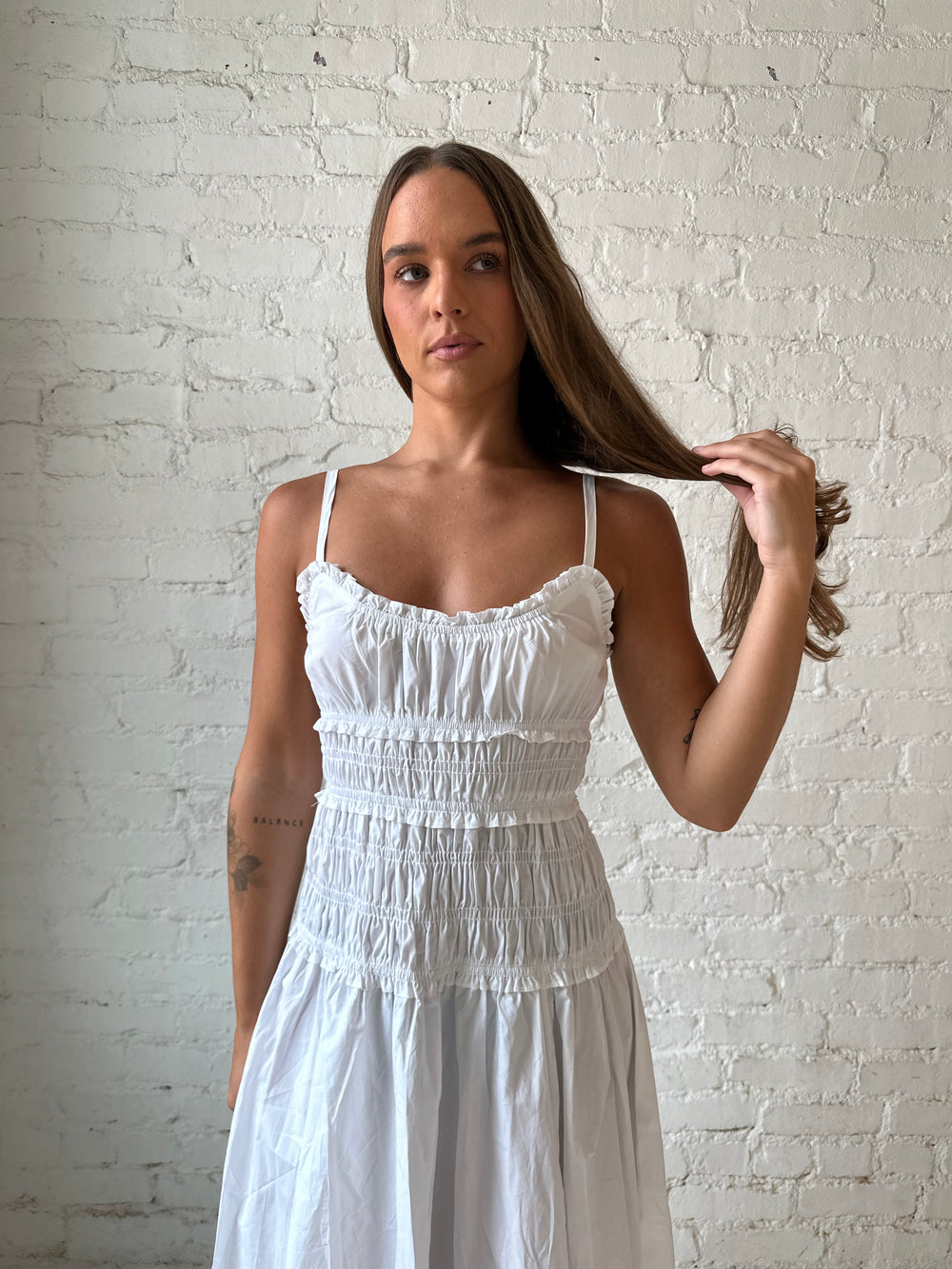 Woman wearing white smocked maxi dress with side slit. 