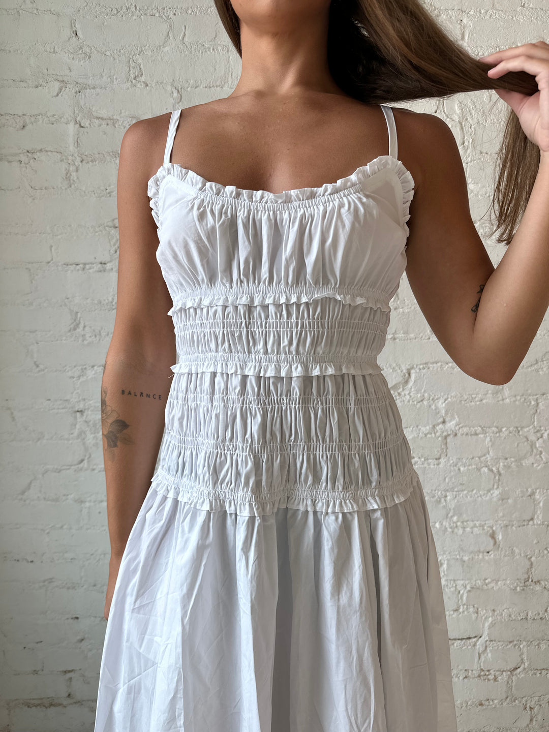 Woman wearing white smocked maxi dress with side slit. 