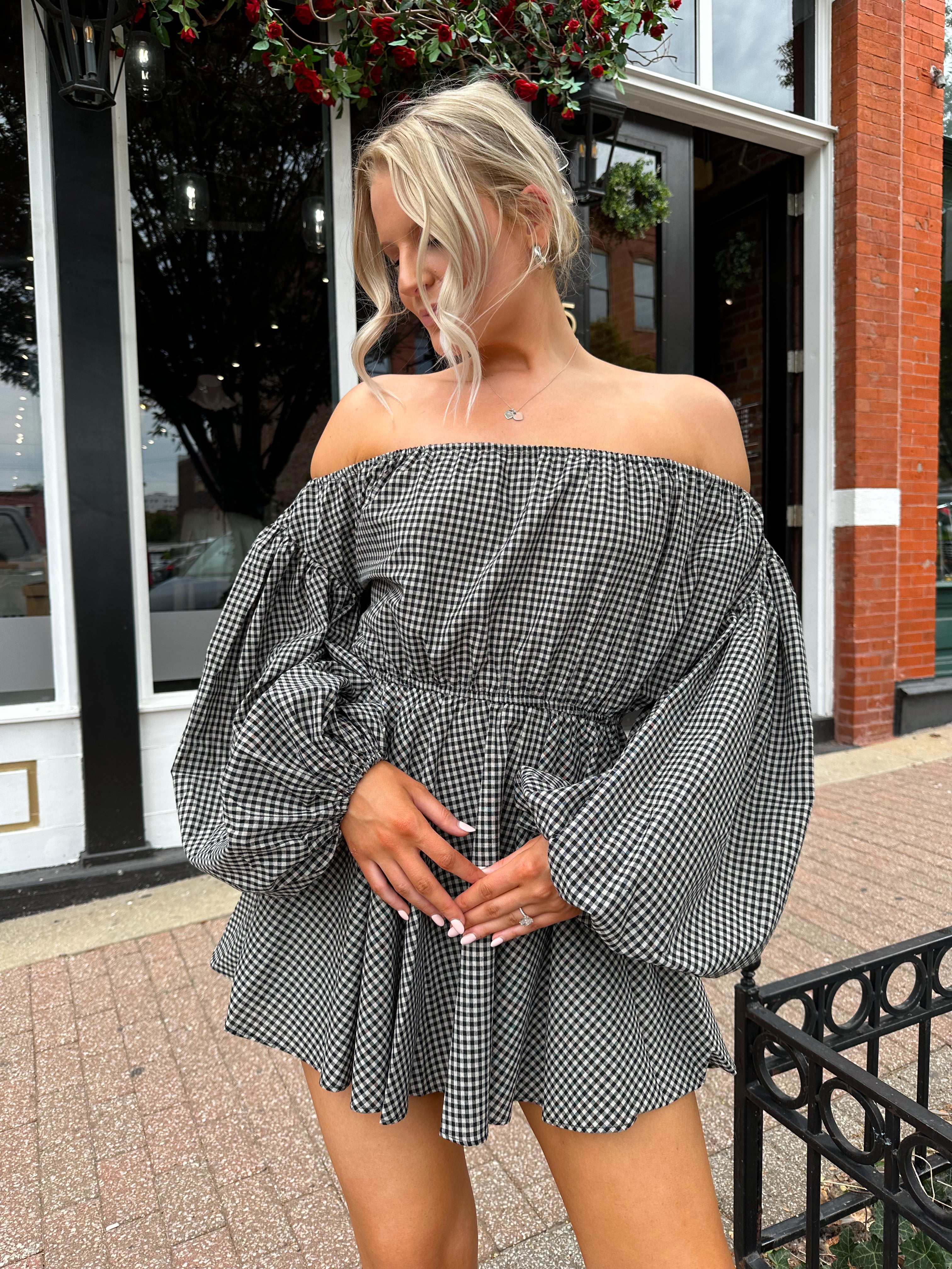 Woman wearing black checkered puff sleeve off the shoulder mini dress. 