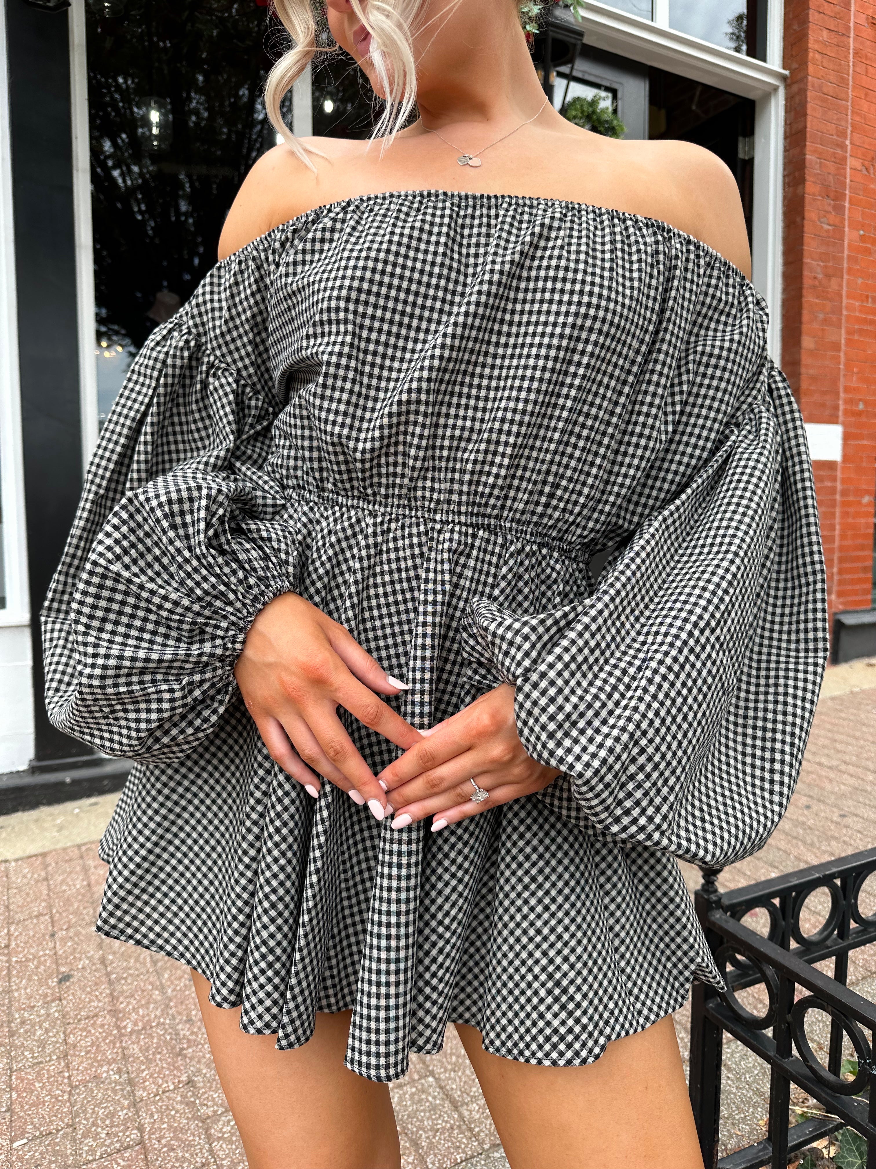 Woman wearing black checkered puff sleeve off the shoulder mini dress. 